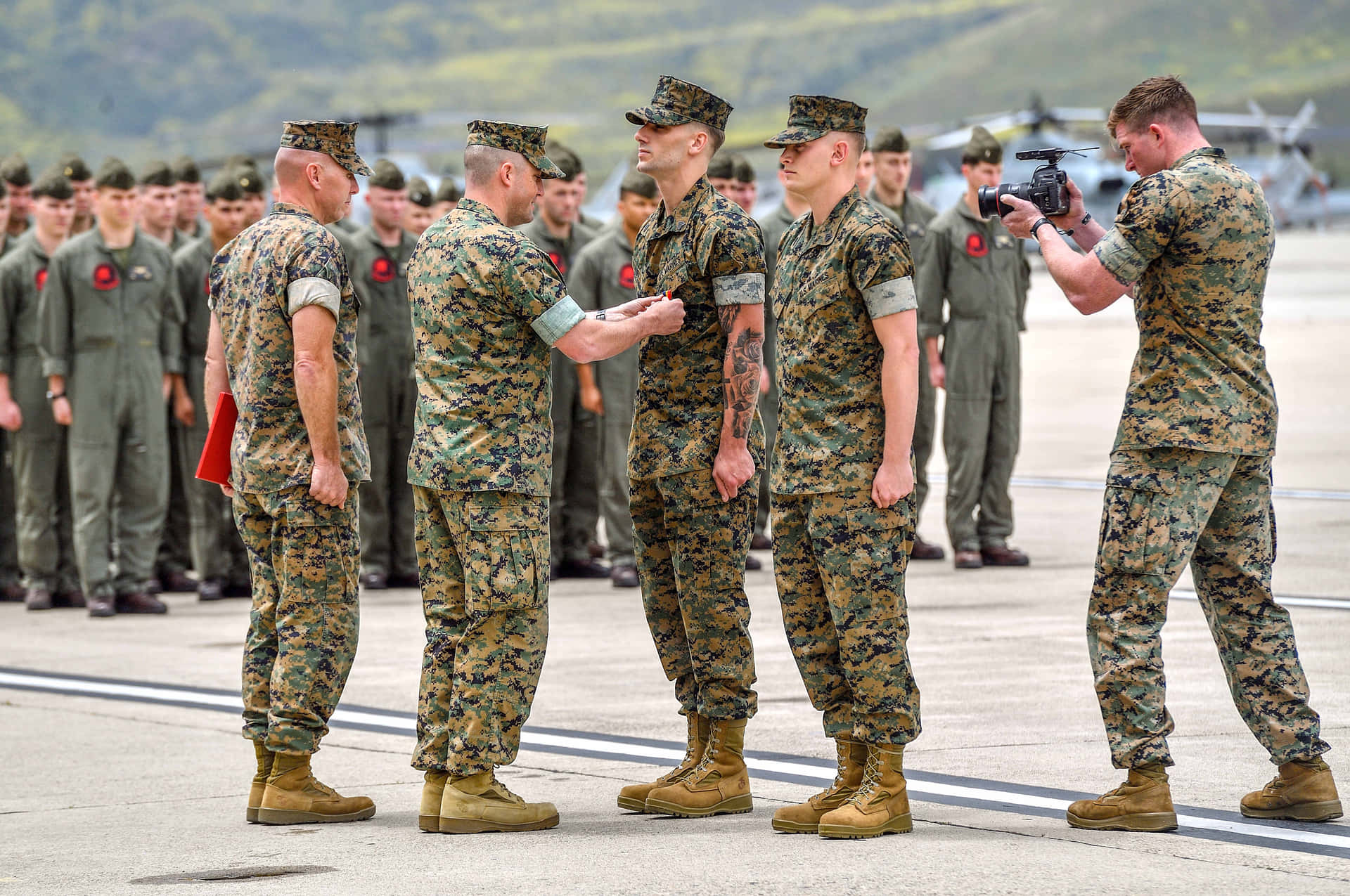 身穿制服的海軍陸戰隊員在機場接受頒獎，有攝影師在場。