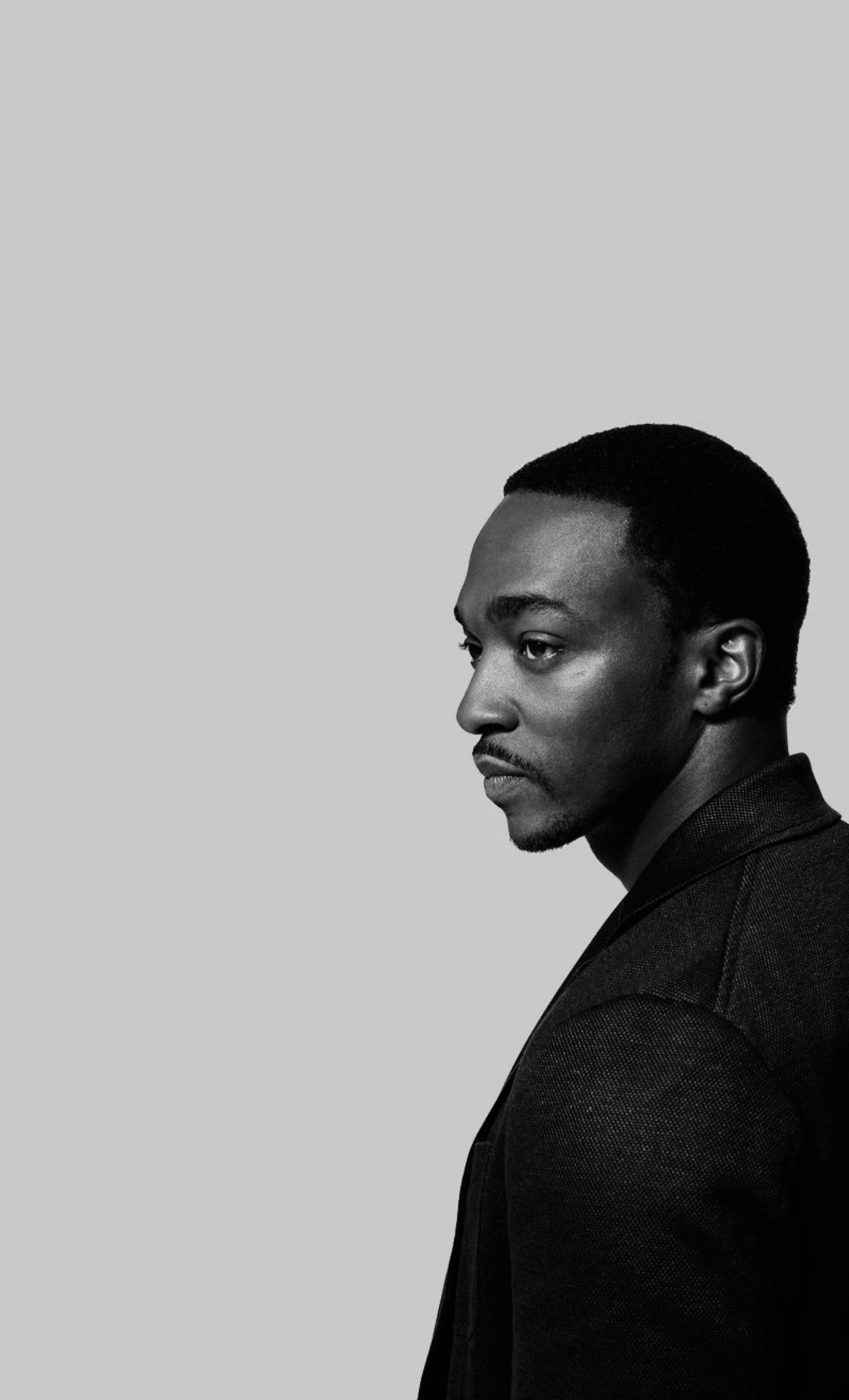 美國演員Anthony Mackie 壁紙 — 一個男人側面的黑白肖像，背景為純灰色，光線柔和。