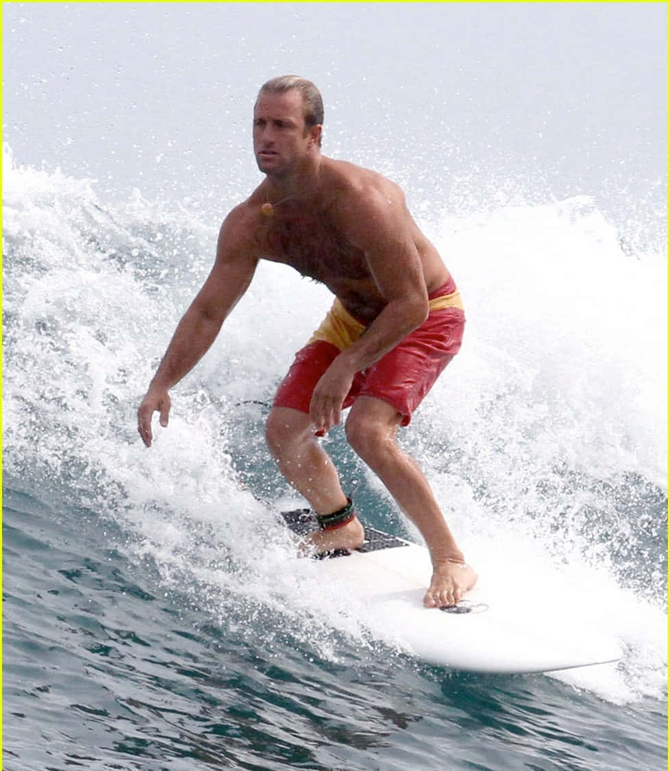 運動型男人穿著紅色短褲在浪上衝浪。
