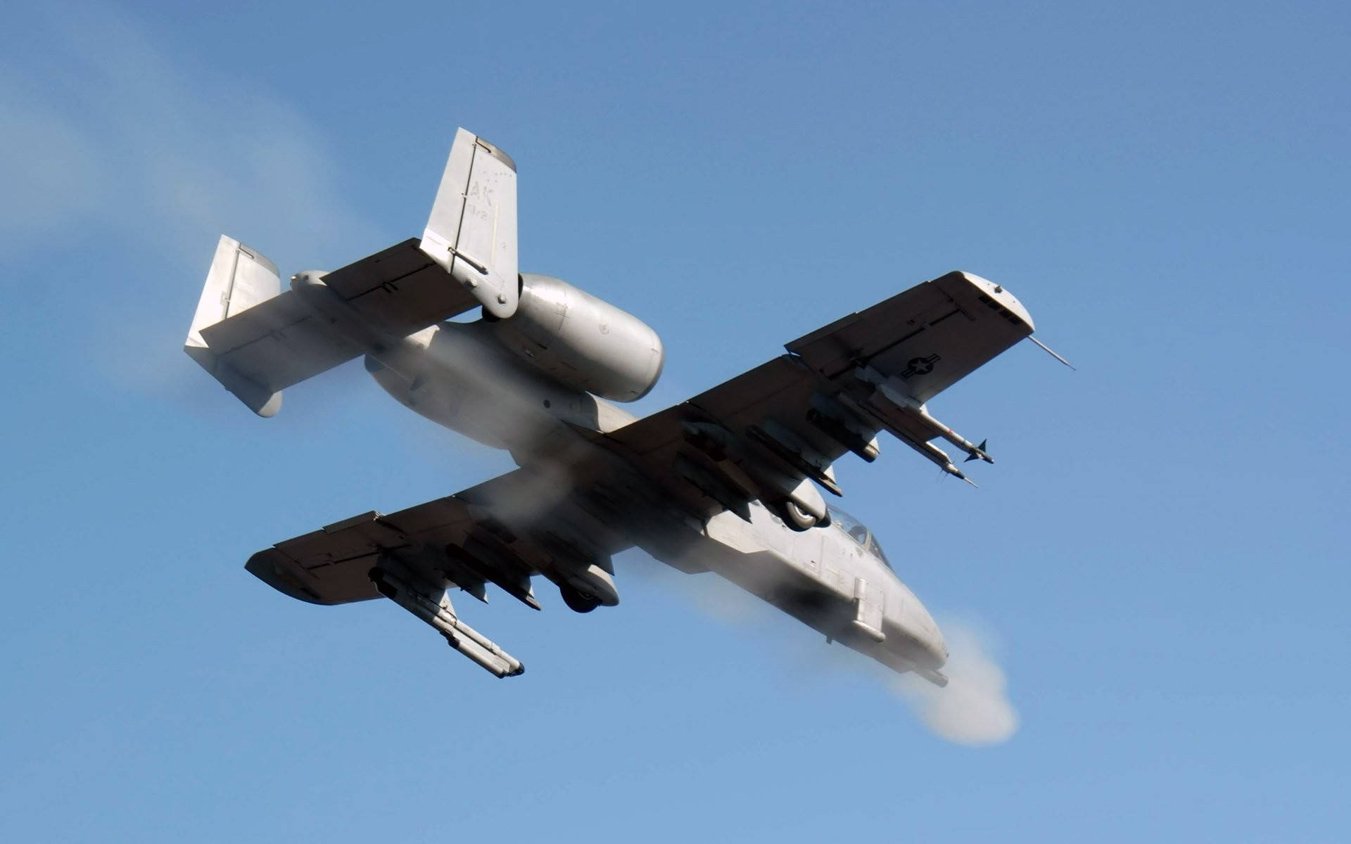 美國空軍 A-10 壁紙 — 一架灰色攻擊機在清澈的藍天中急轉彎，引擎留下白色煙霧痕跡。