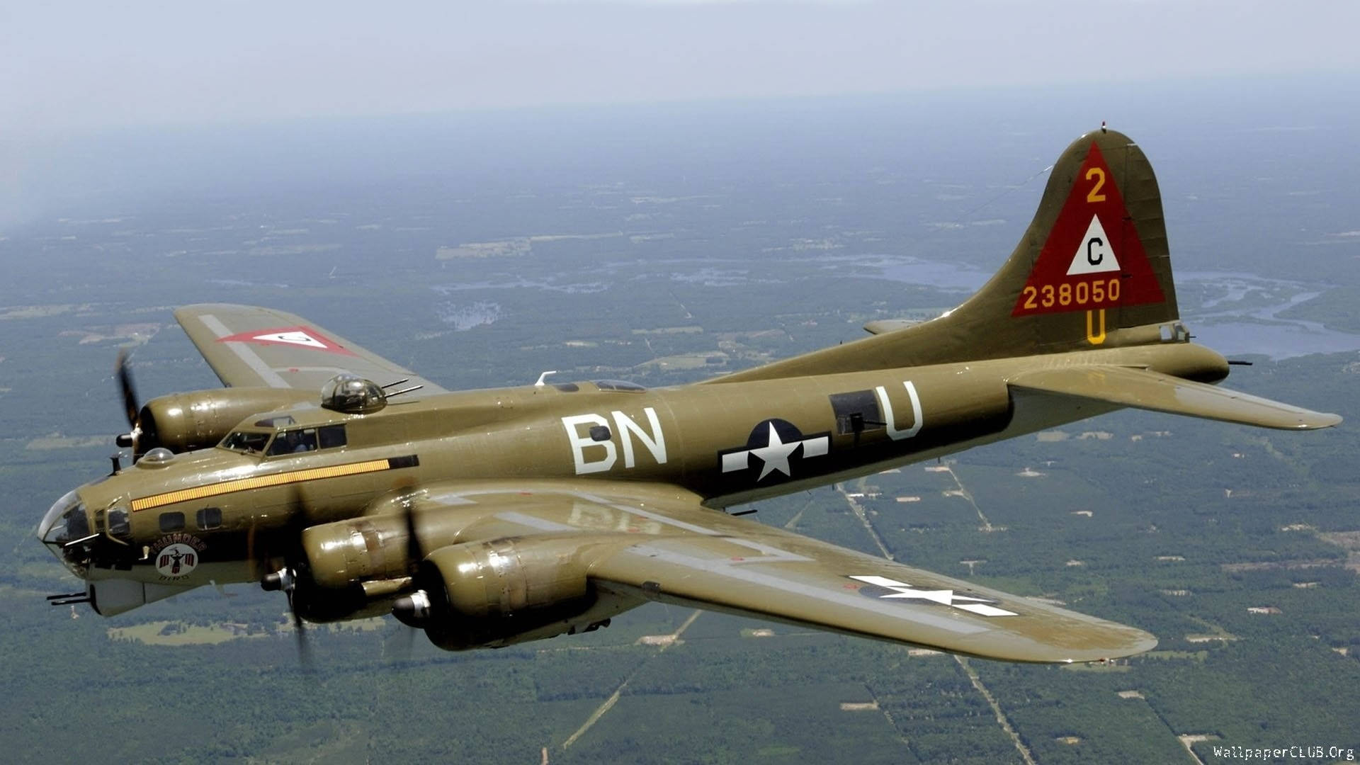 美國空軍 B-17 壁紙 — 一架復古橄欖綠色的B-17飛行堡壘轟炸機在朦朧的天空下翱翔於拼布般的景觀之上。