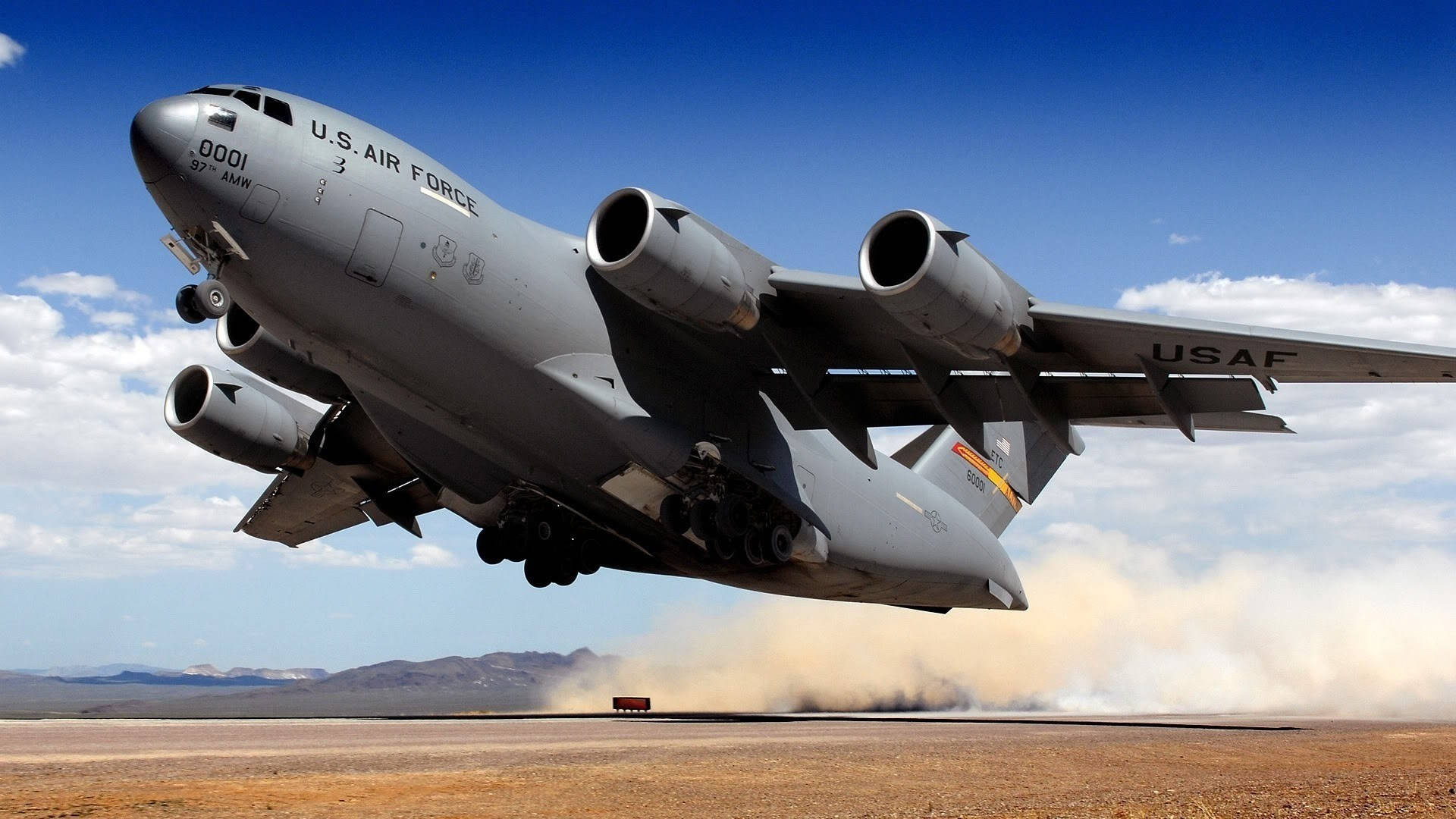 美國空軍 Globemaster 起飛 壁紙 — 一架美國空軍C-17環球霸王III軍用運輸機在晴朗藍天下從沙漠跑道起飛，揚起灰塵。