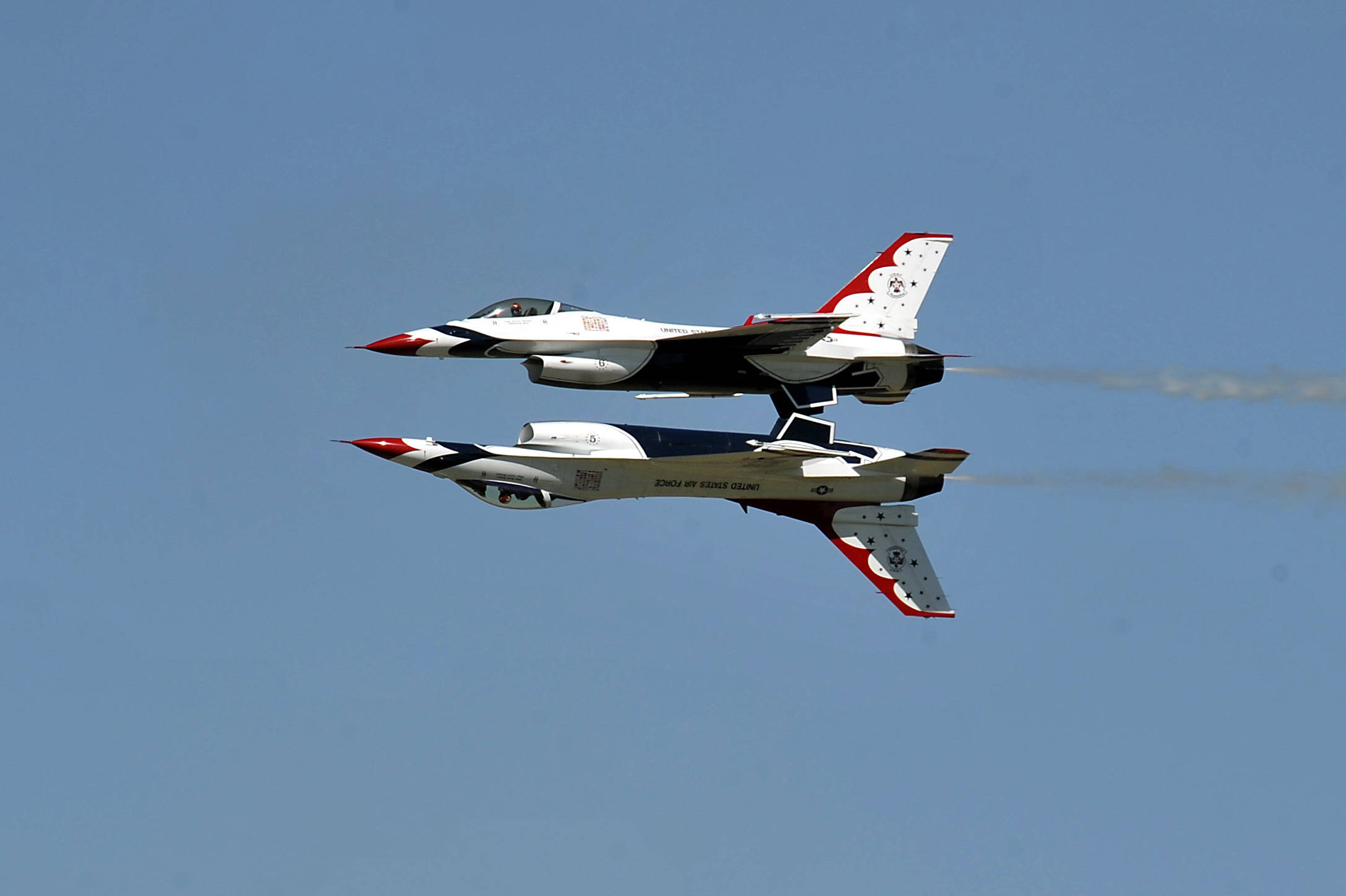 美國空軍雷鳥特技飛行隊 壁紙 — 兩架美國空軍雷鳥戰鬥機在晴朗的藍天下緊密編隊飛行，留下煙霧痕跡。