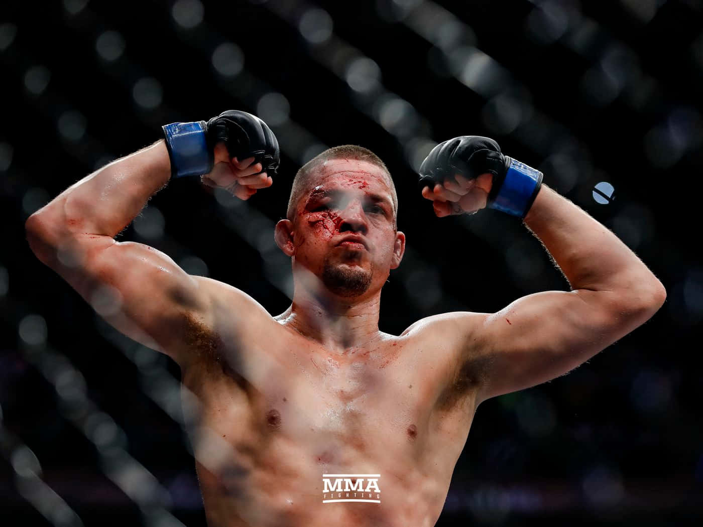 一名滿臉鮮血的勝利MMA拳手在籠內彎曲手臂。