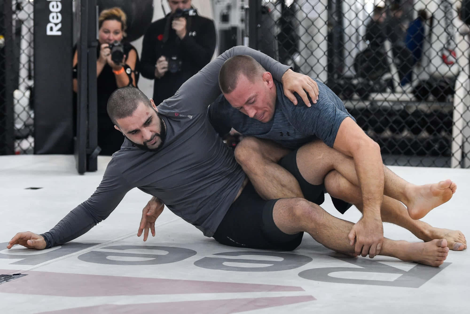 美國綜合格鬥選手帕特·米利蒂奇指導訓練 壁紙 — 兩名拳手在UFC八角籠墊上激烈纏鬥，攝影師捕捉動作。