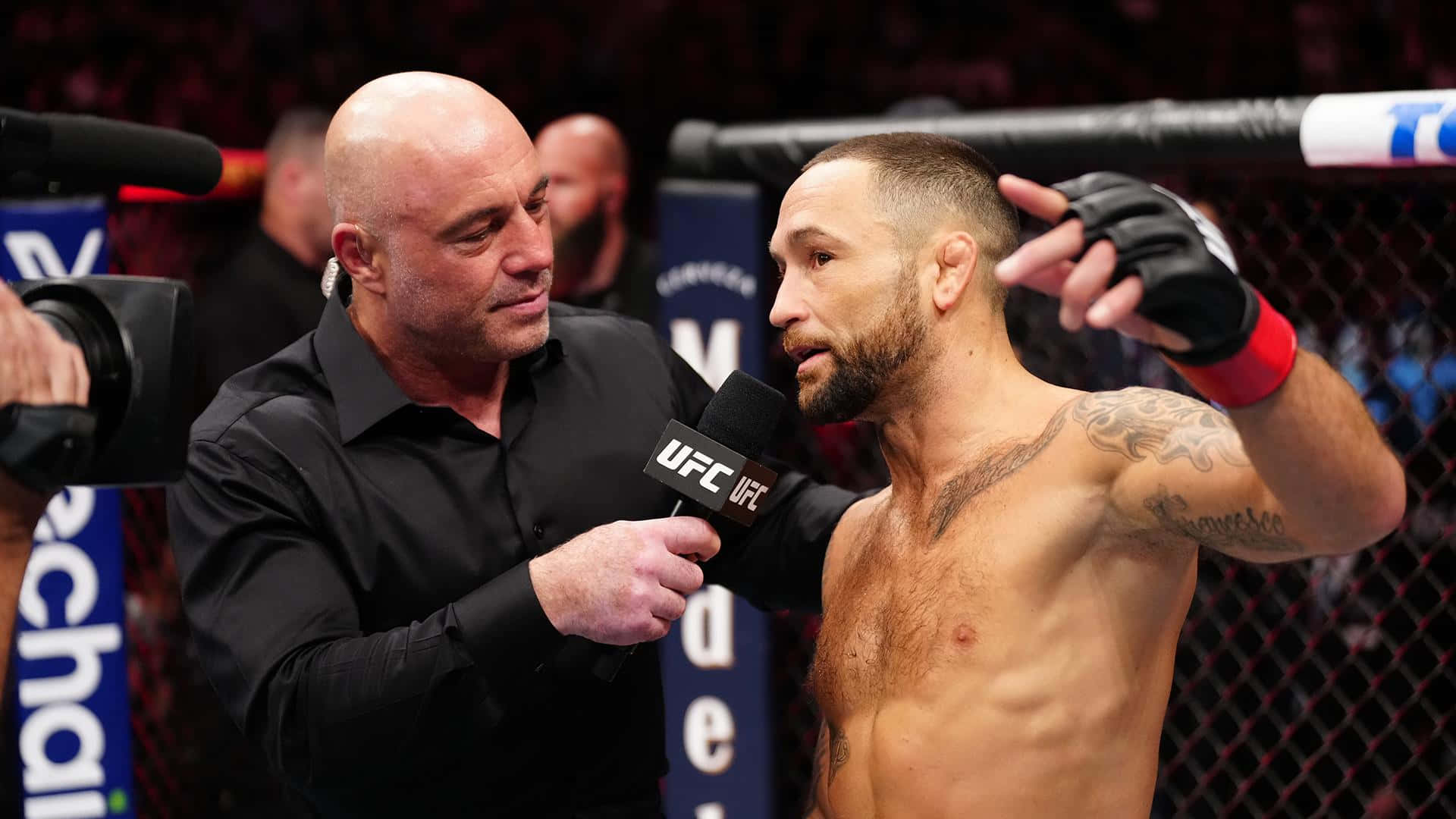 美國綜合格鬥選手弗蘭基·愛德華 UFC 281 八角籠訪談 壁紙 — 一位有紋身的UFC拳手在籠內接受光頭主持人的訪問，現場有明亮的燈光和攝影機。