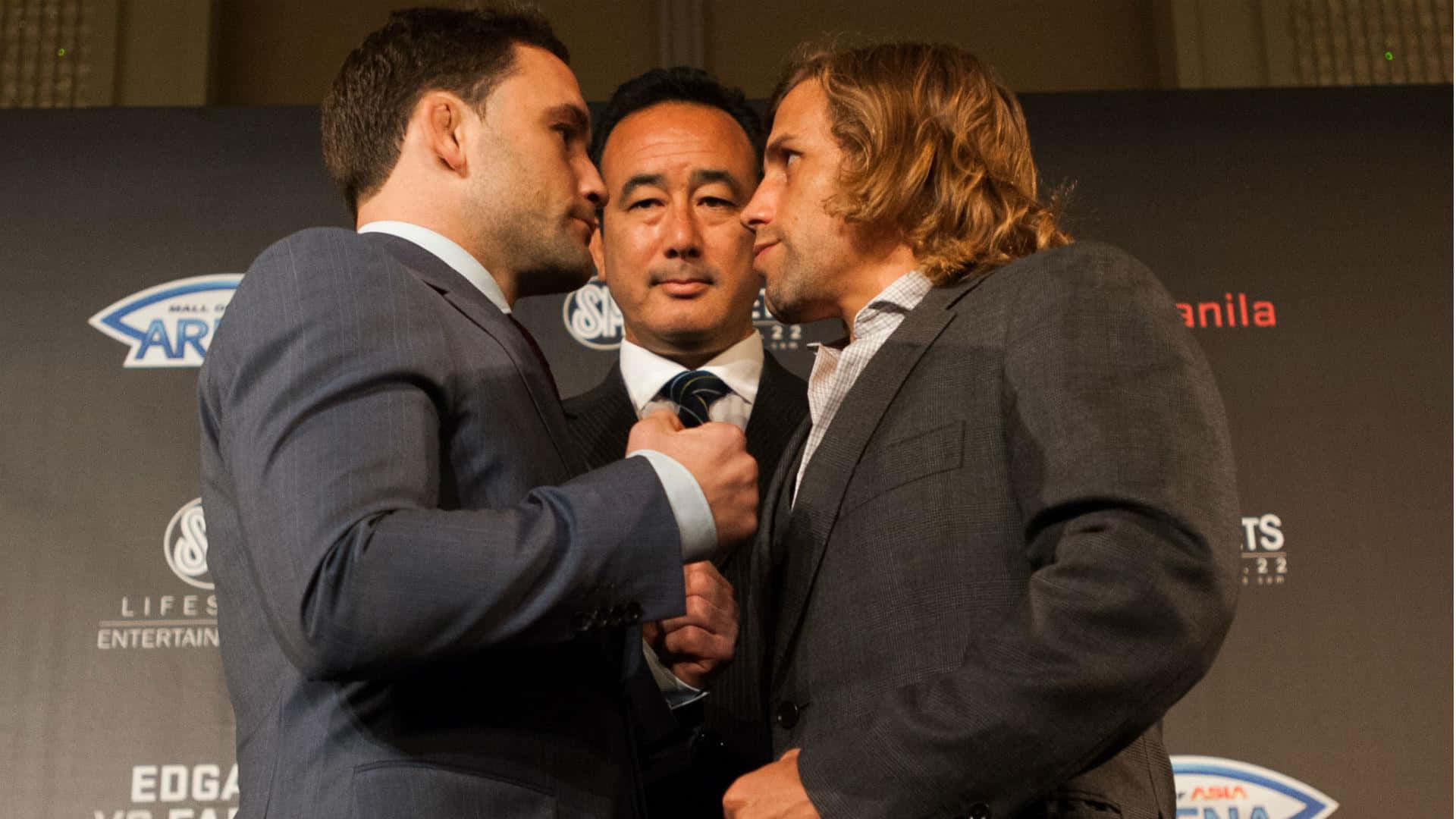 美國綜合格鬥選手弗蘭基·愛德華於 UFC 馬尼拉記者會 壁紙 — 兩名身穿西裝的男子在記者會上鼻對鼻對峙，第三名男子則在他們之間拿著麥克風。