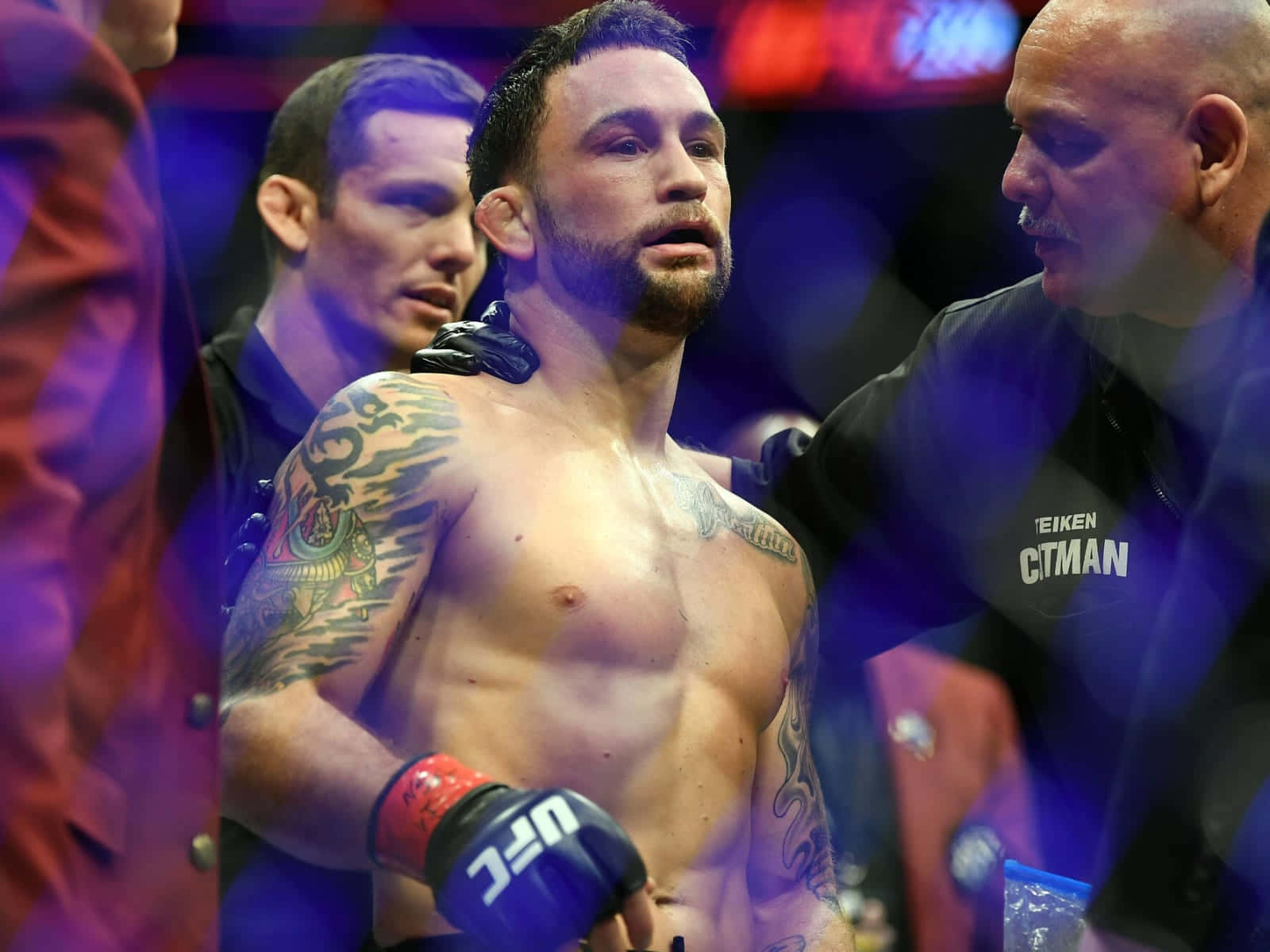 美國綜合格鬥選手弗蘭基·愛德華於 UFC 222 比賽後 壁紙 — 一個汗流浹背、有紋身的拳手戴著UFC手套站在擂台上，裁判在明亮的場館燈光下檢查他。