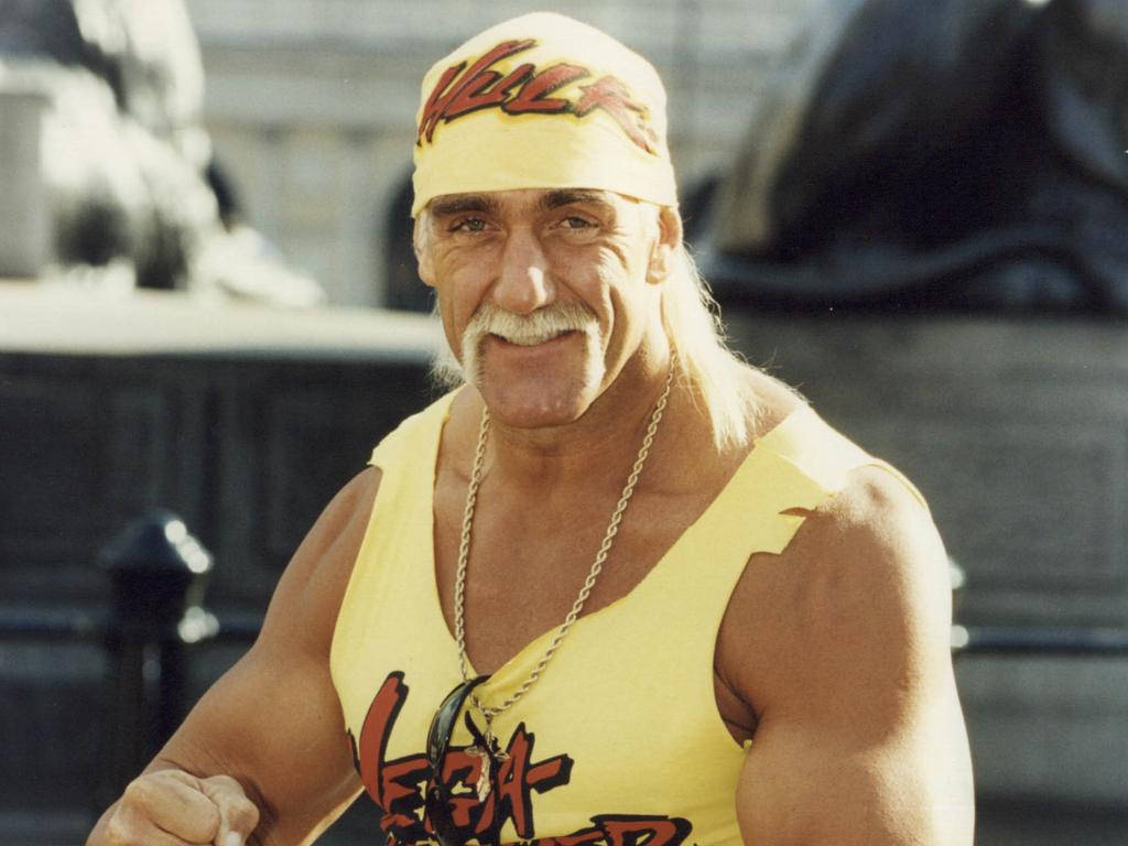 美國職業摔角手 Hulk Hogan 當場演出 壁紙 — Hulk Hogan 身穿標誌性黃色摔角裝備，帶著招牌鬍子和頭帶，自信地微笑。