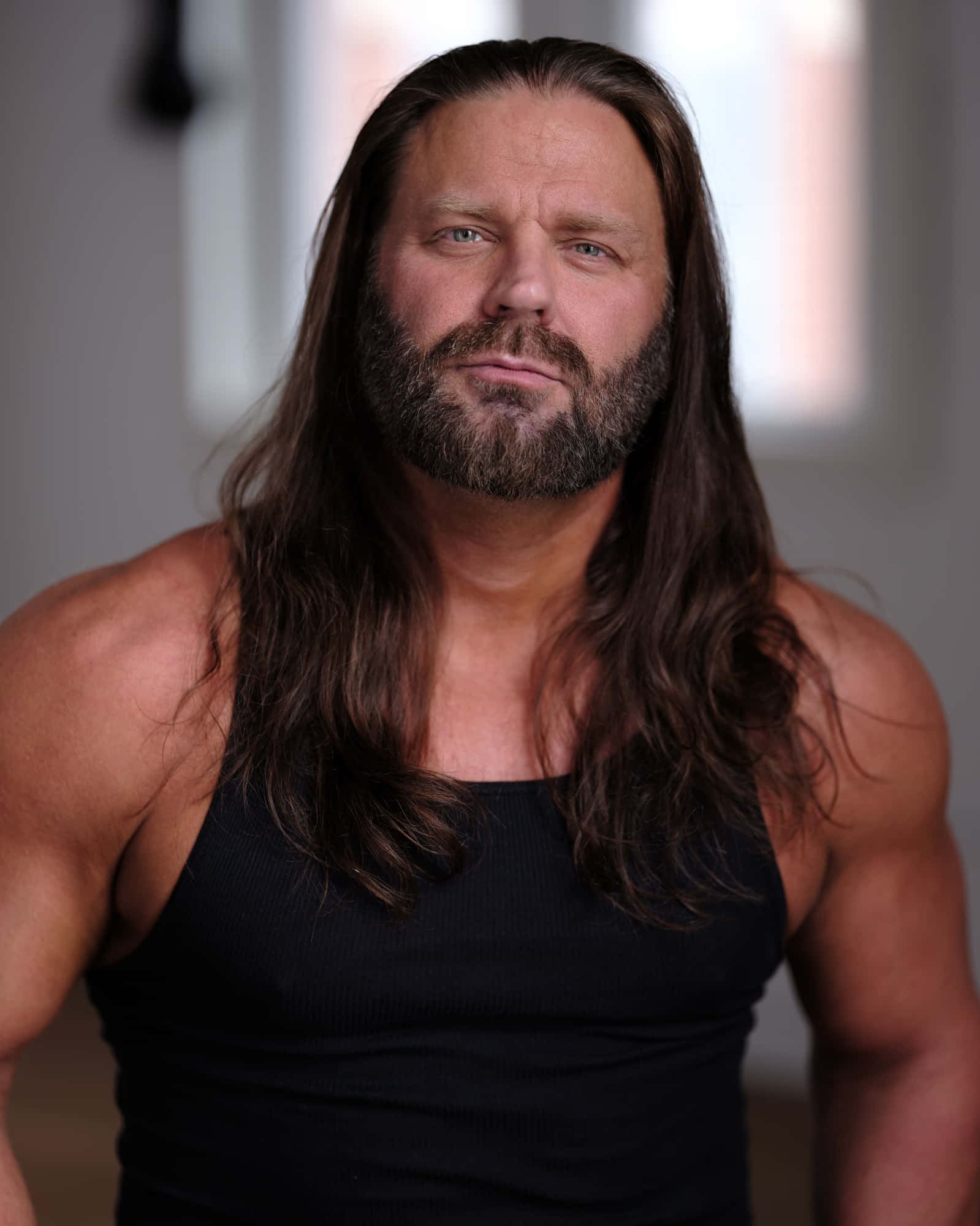 美國職業摔角手James Storm穿黑色背心 壁紙 — 一個肌肉發達、留著黑色長髮和鬍鬚的男人，穿著黑色背心，專注地凝視著鏡頭。
