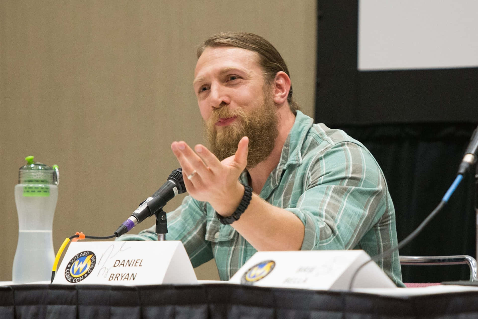 Daniel Bryan 在會議座談會上拿著麥克風和水瓶發言。