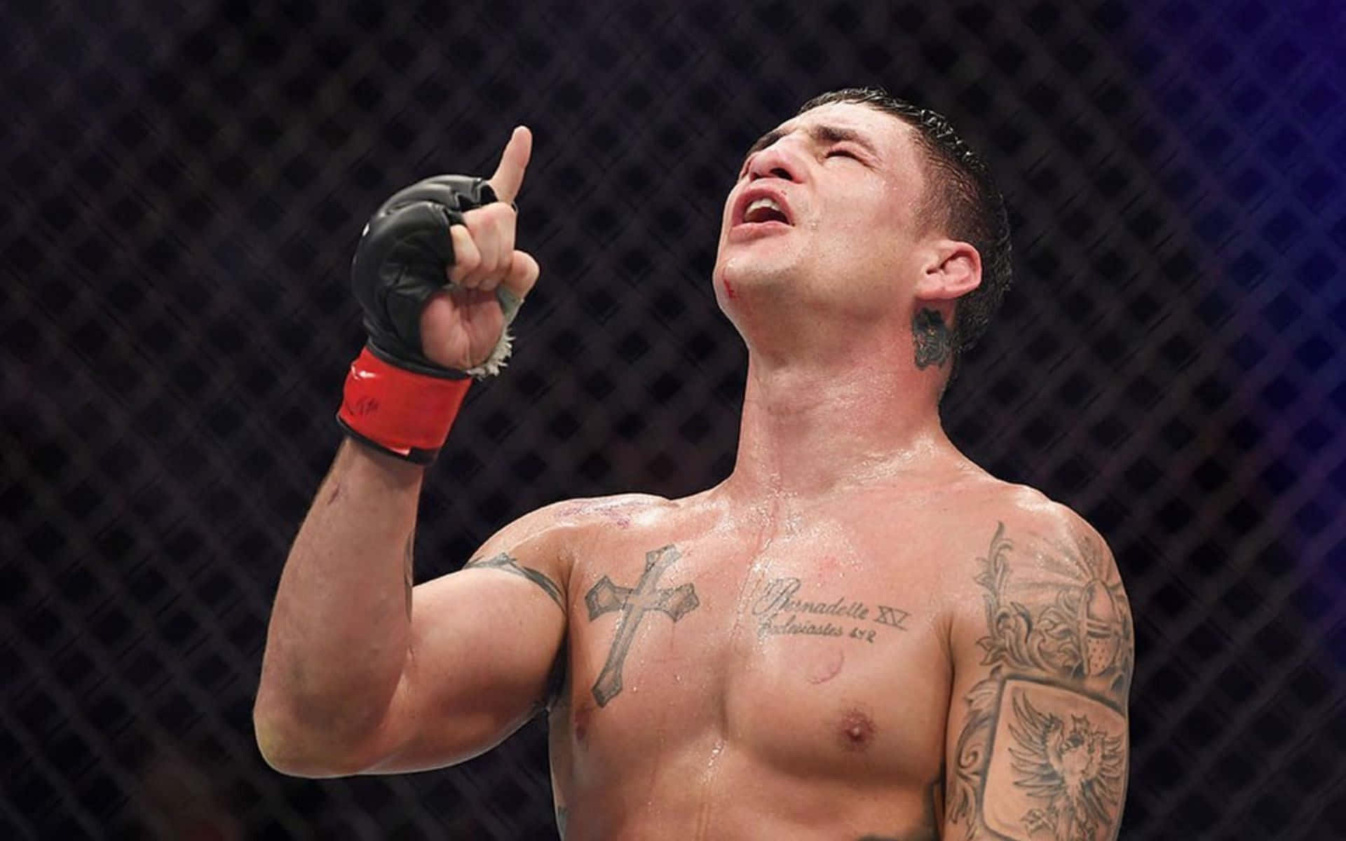 一個勝利的MMA拳手，帶有紋身，在籠內舉起一根手指以示勝利。