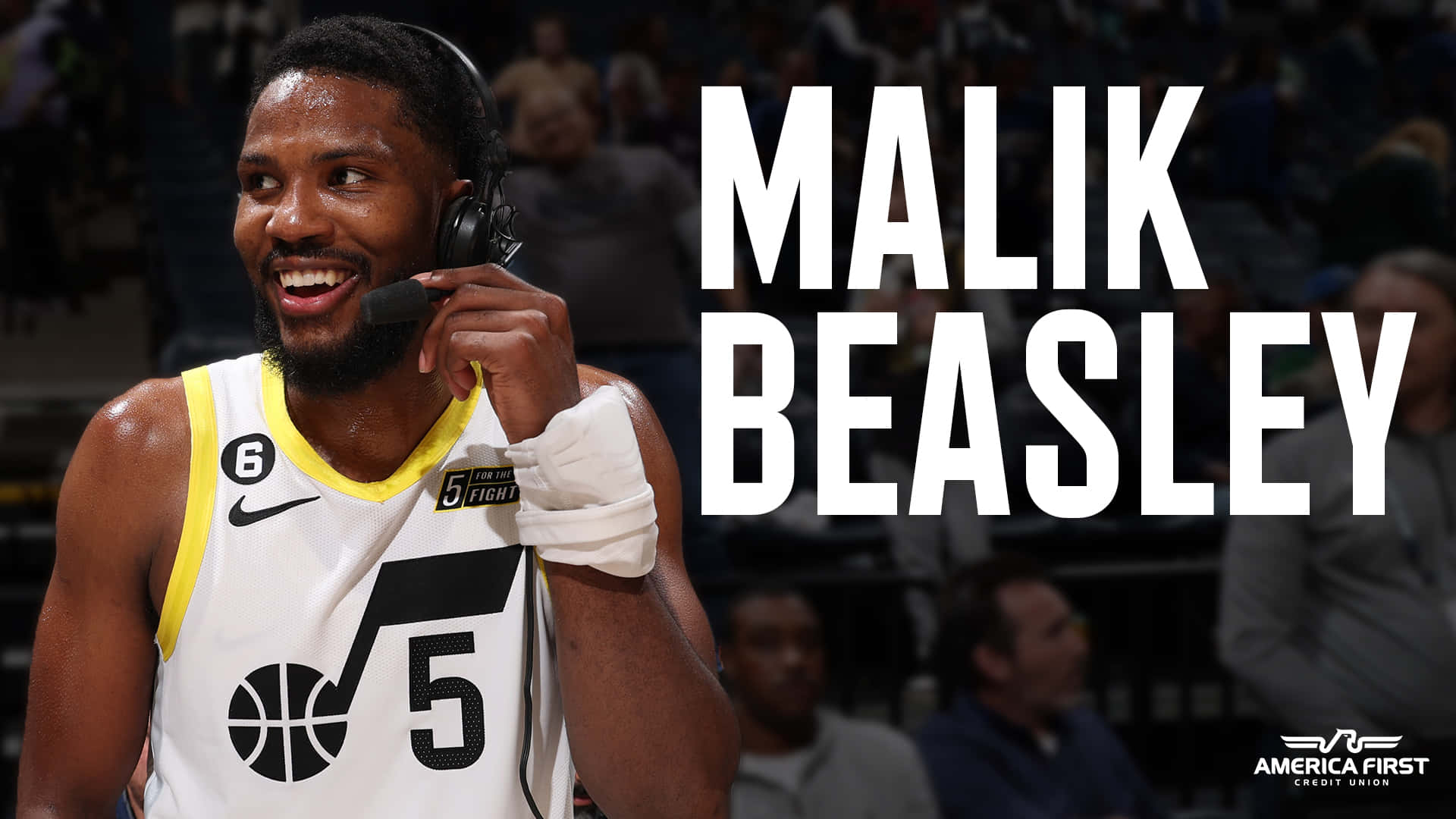 美國職業籃球員馬利克·比斯利海報藝術 壁紙 — 籃球運動員 Malik Beasley 在比賽中戴著耳機，身穿白色和黃色5號球衣，露出燦爛的笑容。