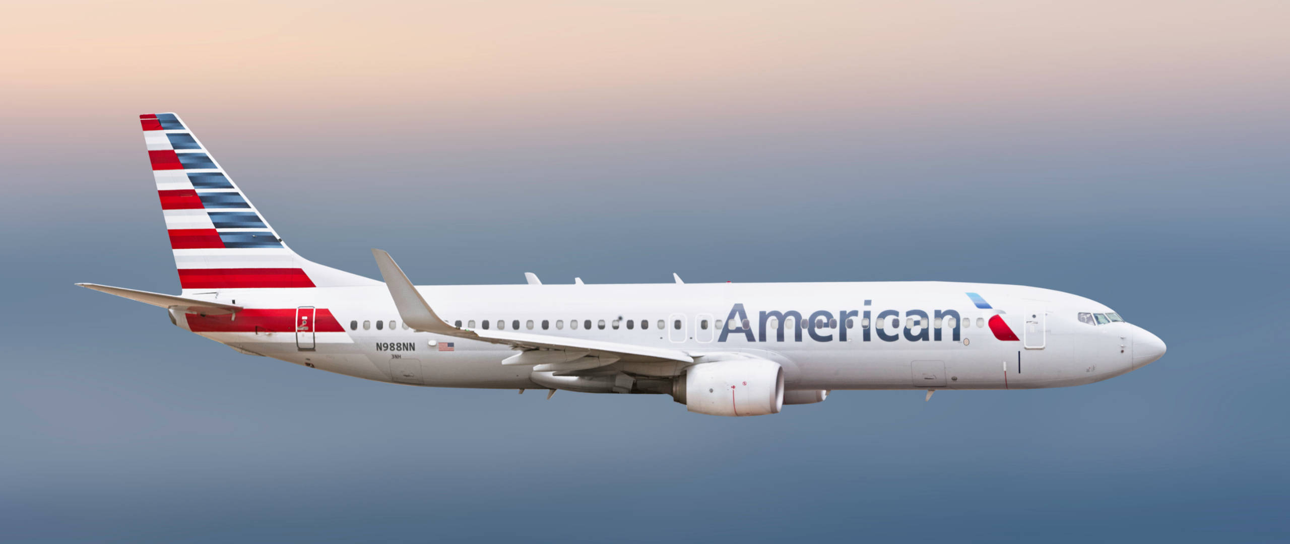 美國航空A319空中巴士N988AL 壁紙 — 美國航空波音737在黃昏時分，於柔和漸變的天空中優雅翱翔。