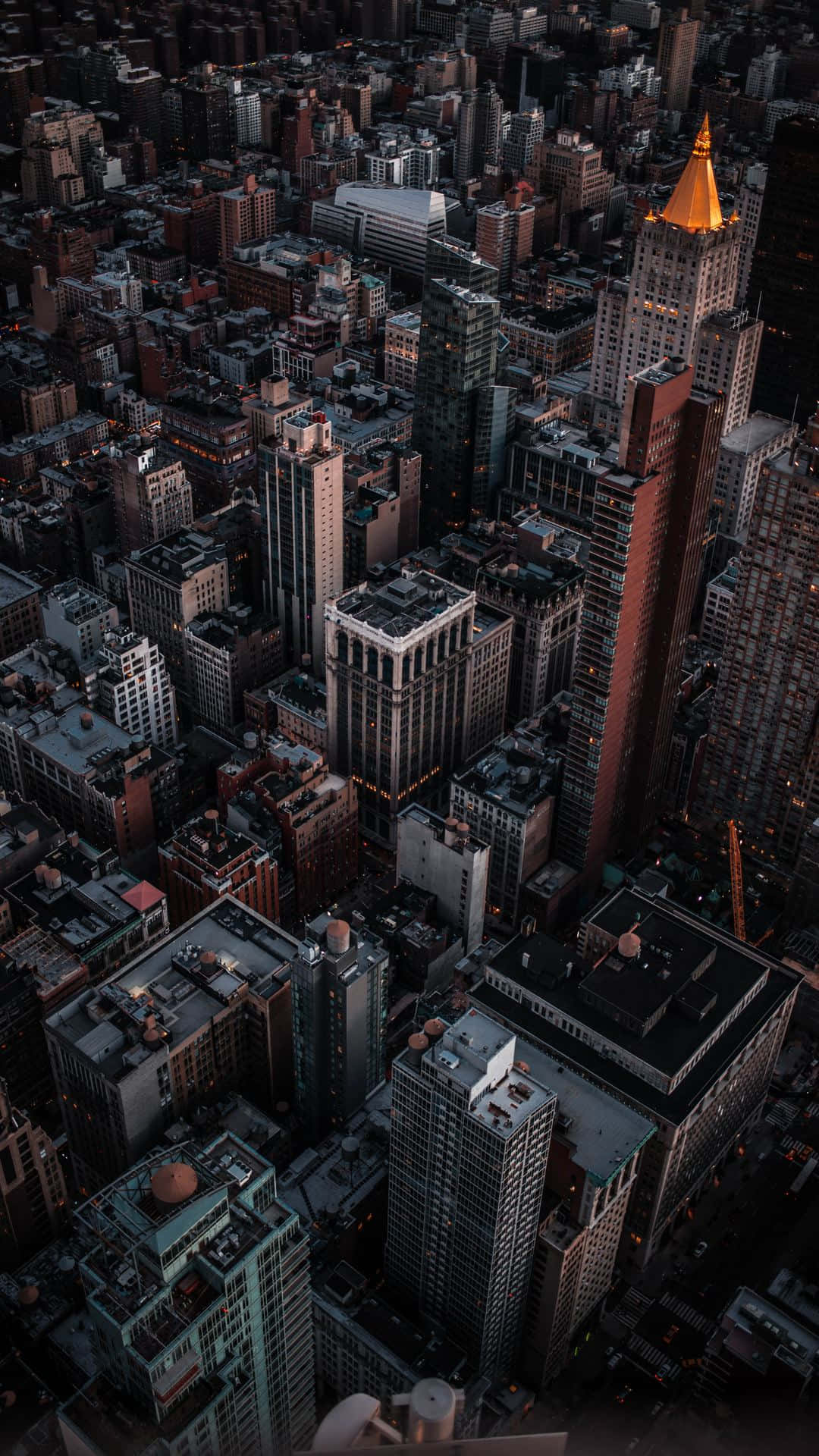 黃昏時分密集城市的鳥瞰圖，金色尖塔在黑暗建築物上方發光。
