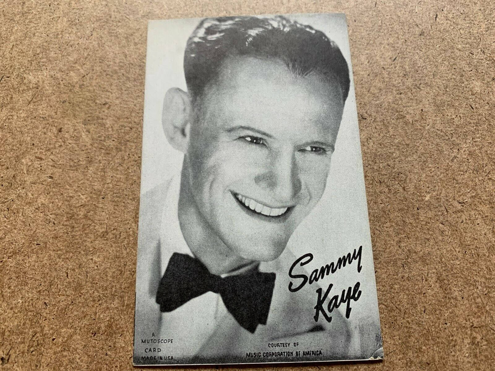 復古Mutoscope卡片，展示微笑的音樂家Sammy Kaye戴著蝴蝶結領結在軟木板上。