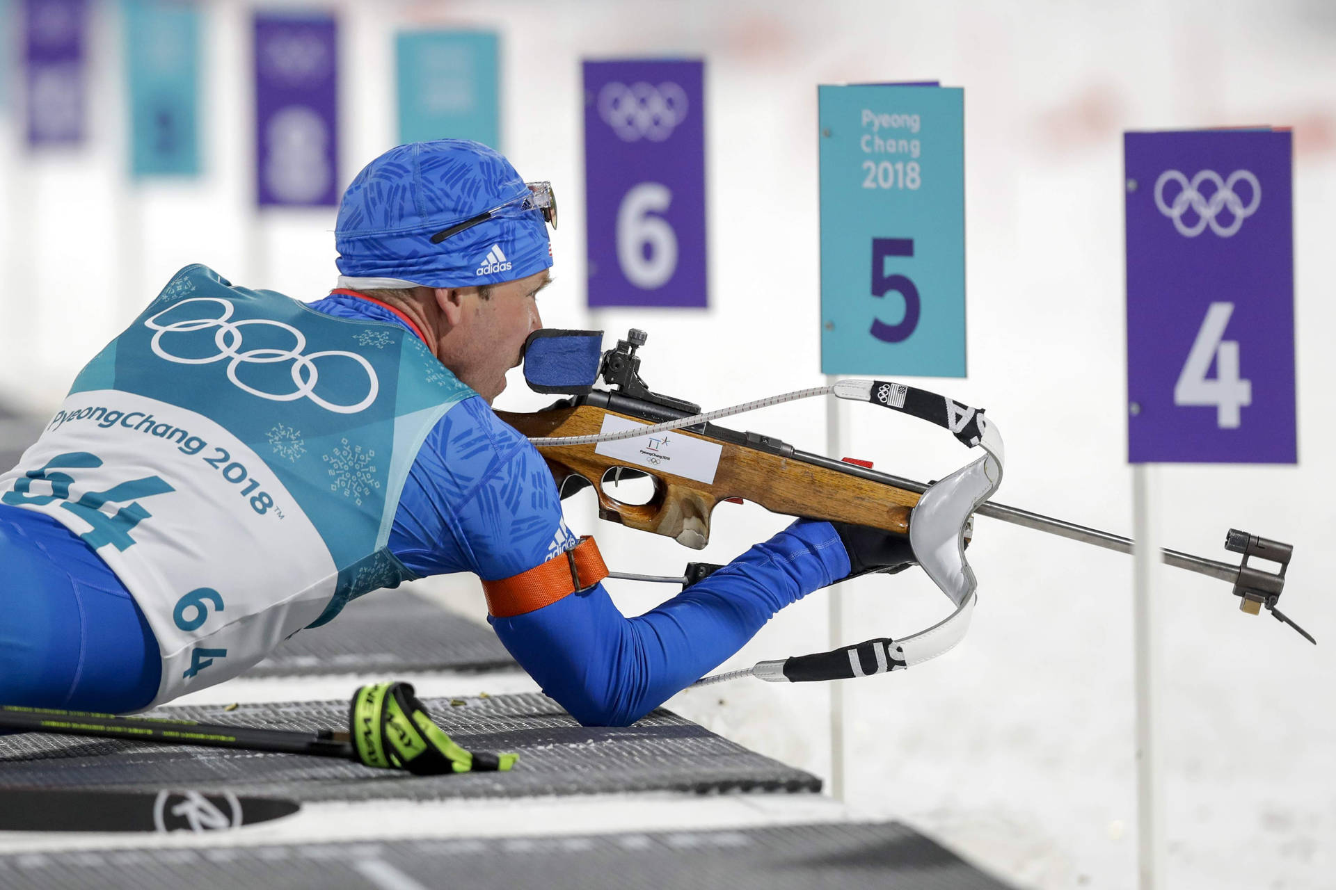 美國越野滑雪射擊選手洛厄爾·貝利2018冬季奧運會 壁紙 — 一名身穿藍色制服嘅冬季兩項運動員喺2018年平昌冬奧會期間，專注地瞄準步槍。
