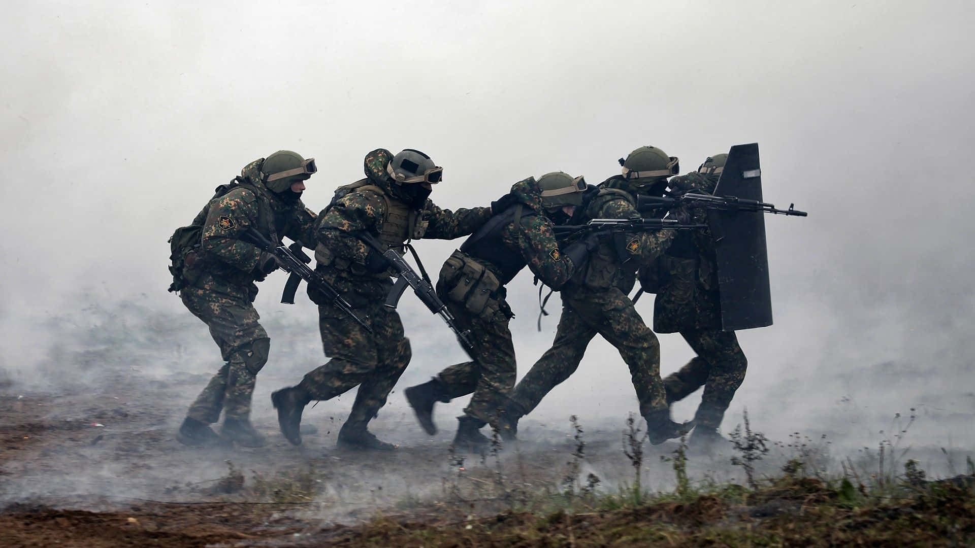 身穿迷彩裝備的士兵穿過煙霧，手持步槍和盾牌前進。