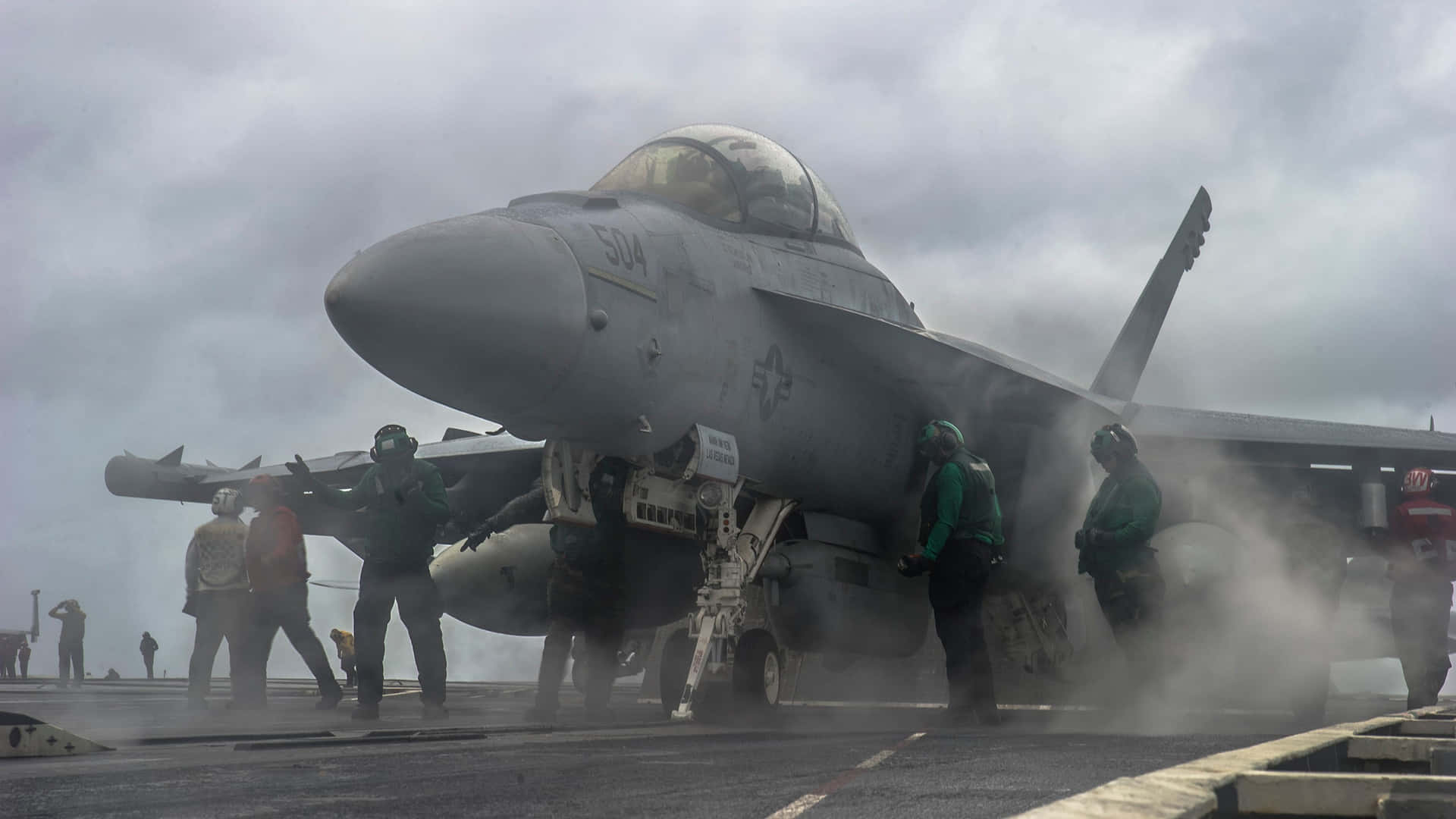軍事機組人員在航空母艦甲板上為戰鬥機進行維護。
