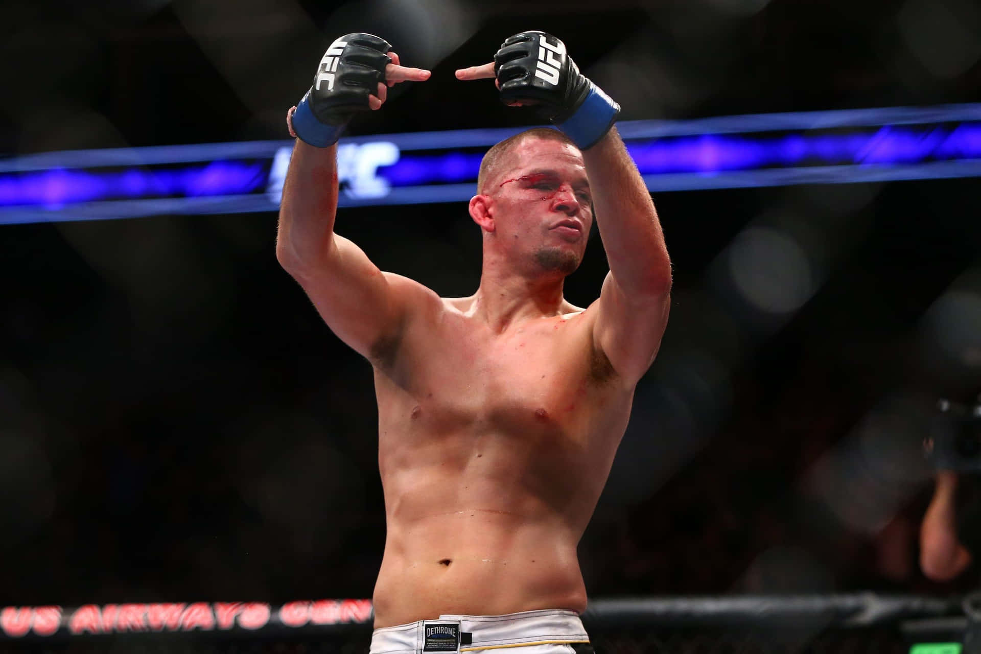 MMA拳手喺八角籠內以沾血嘅臉同高舉嘅手套慶祝勝利。