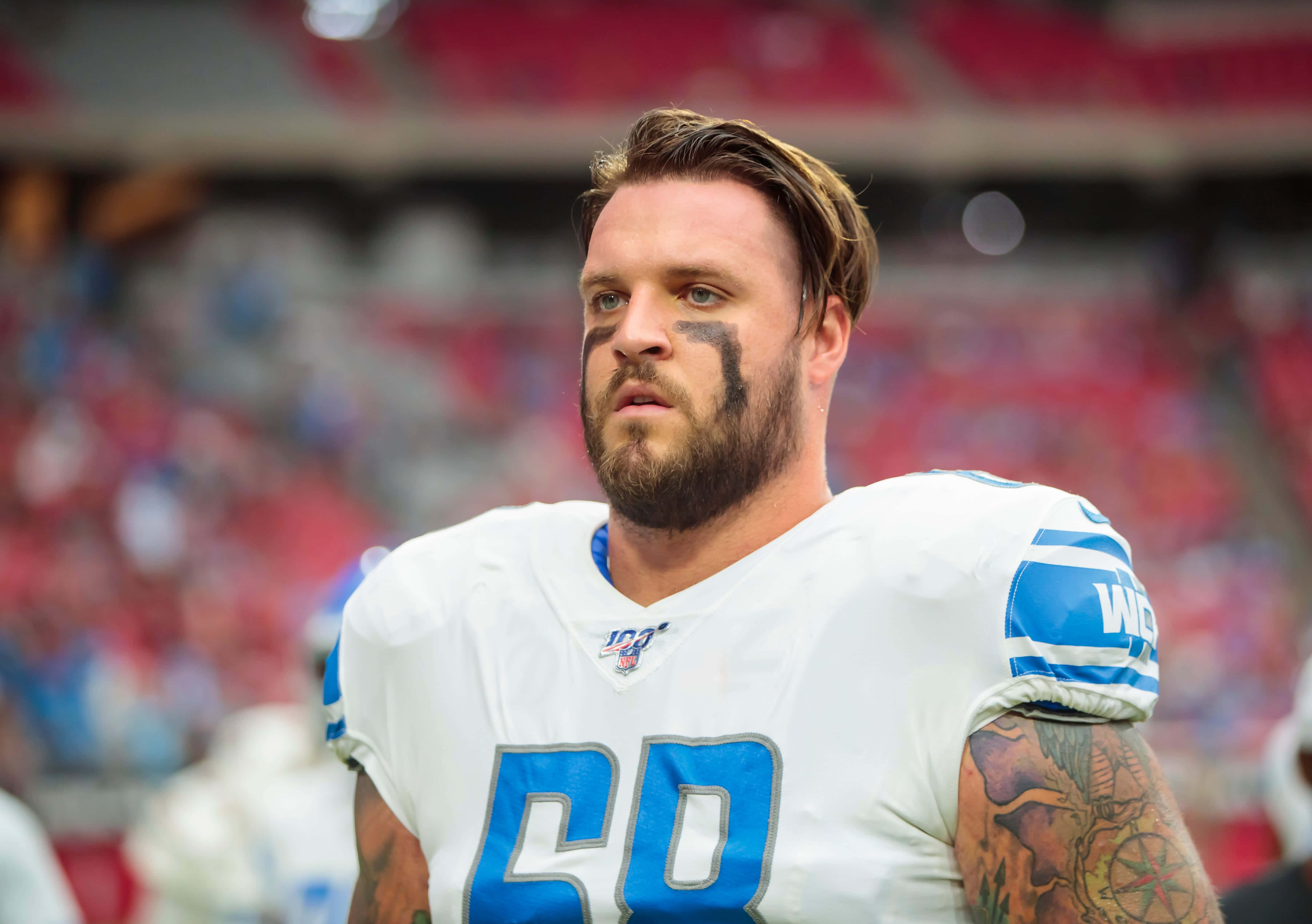 美國運動員泰勒·德克爾 壁紙 — 一位專注的NFL球員，留著鬍鬚和臉部彩繪，身穿帶有藍色58號的白色球衣站在球場上。