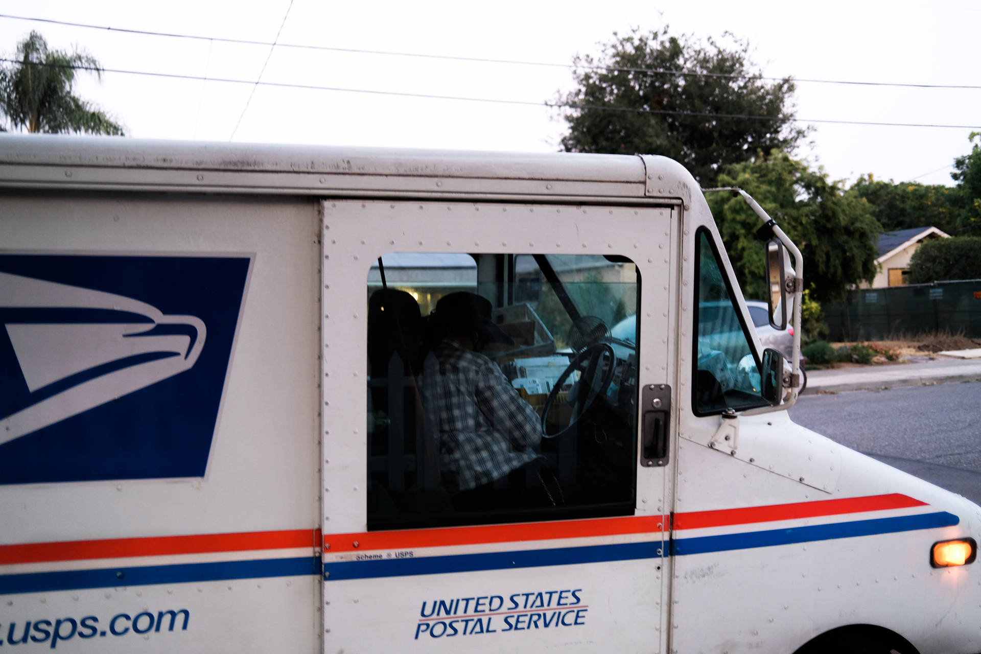 住宅區街道上，USPS送貨車司機穿著格仔恤衫。