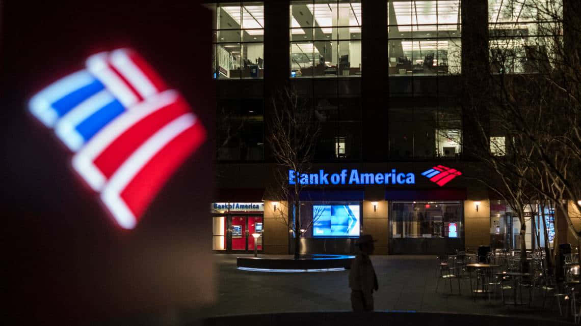 夜間，一個人走過燈火通明的Bank of America大樓，前景有發光的標誌。