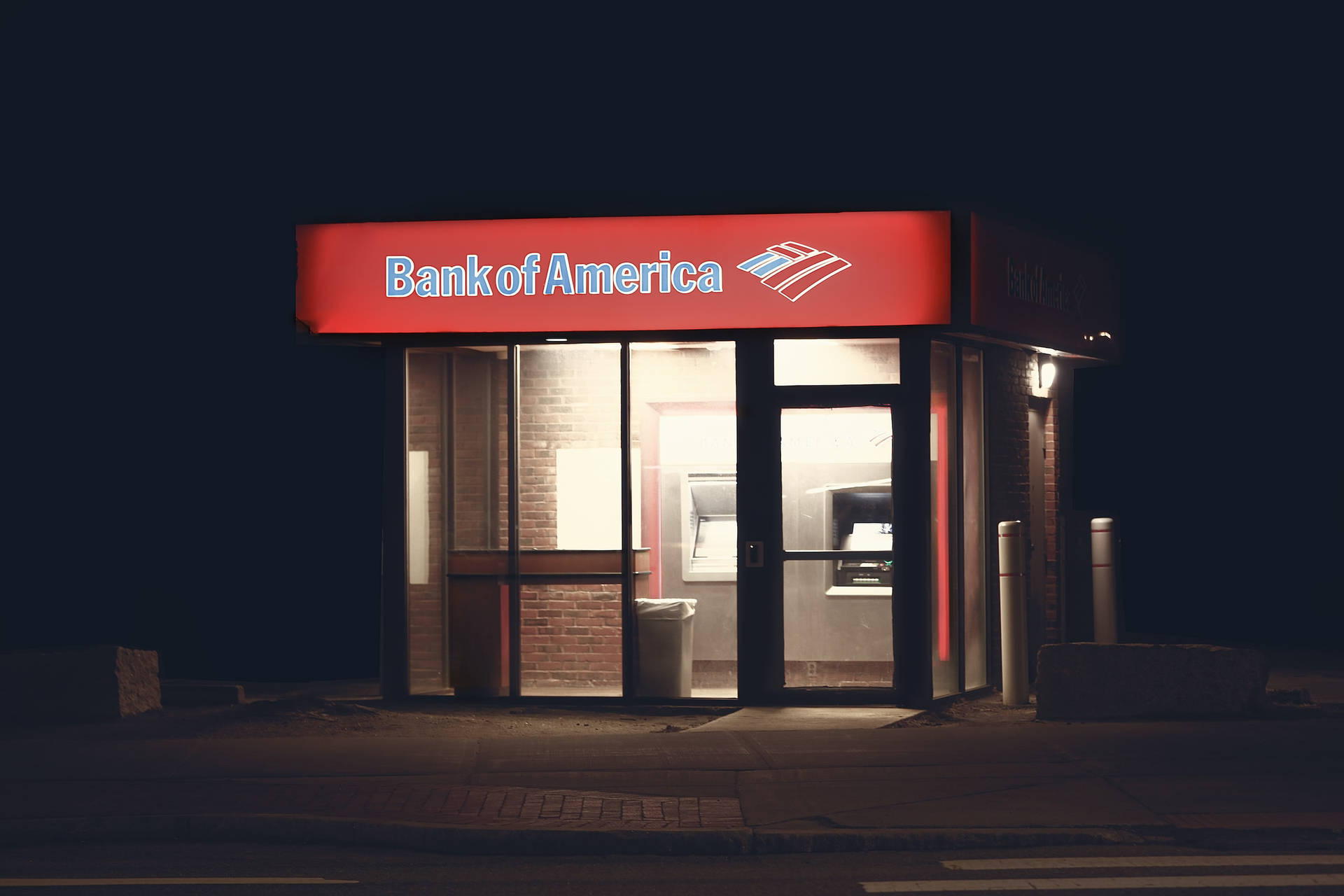 夜晚喺城市街道上亮起嘅Bank of America自動櫃員機亭。