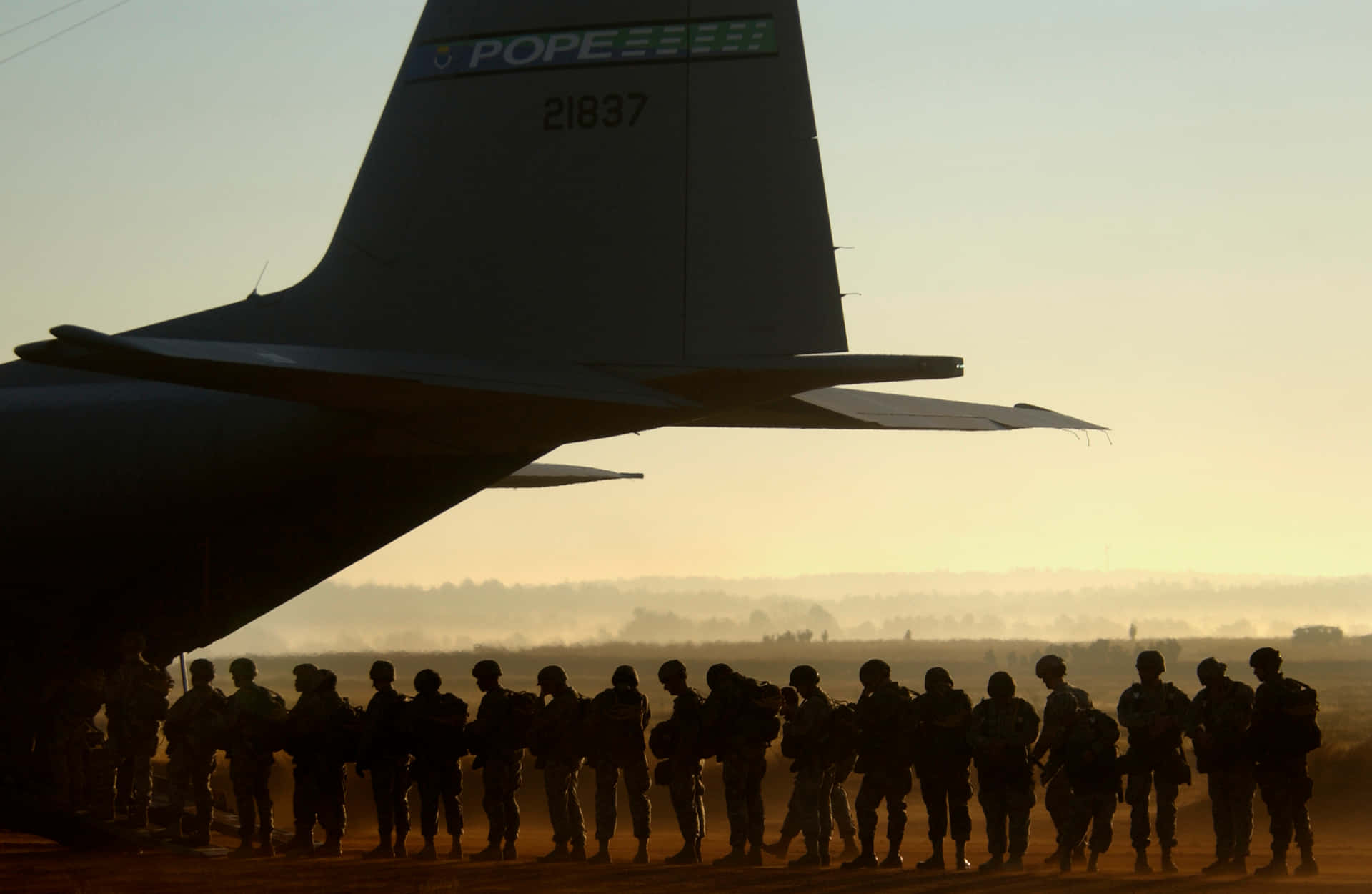 剪影士兵在黎明時分站在軍用飛機旁排隊。