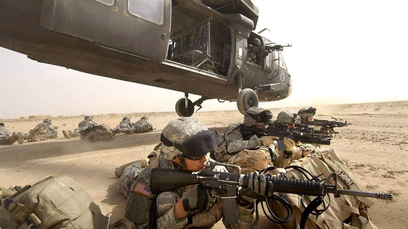 穿著沙漠裝備的士兵在一架盤旋的軍用直升機附近尋找掩護。