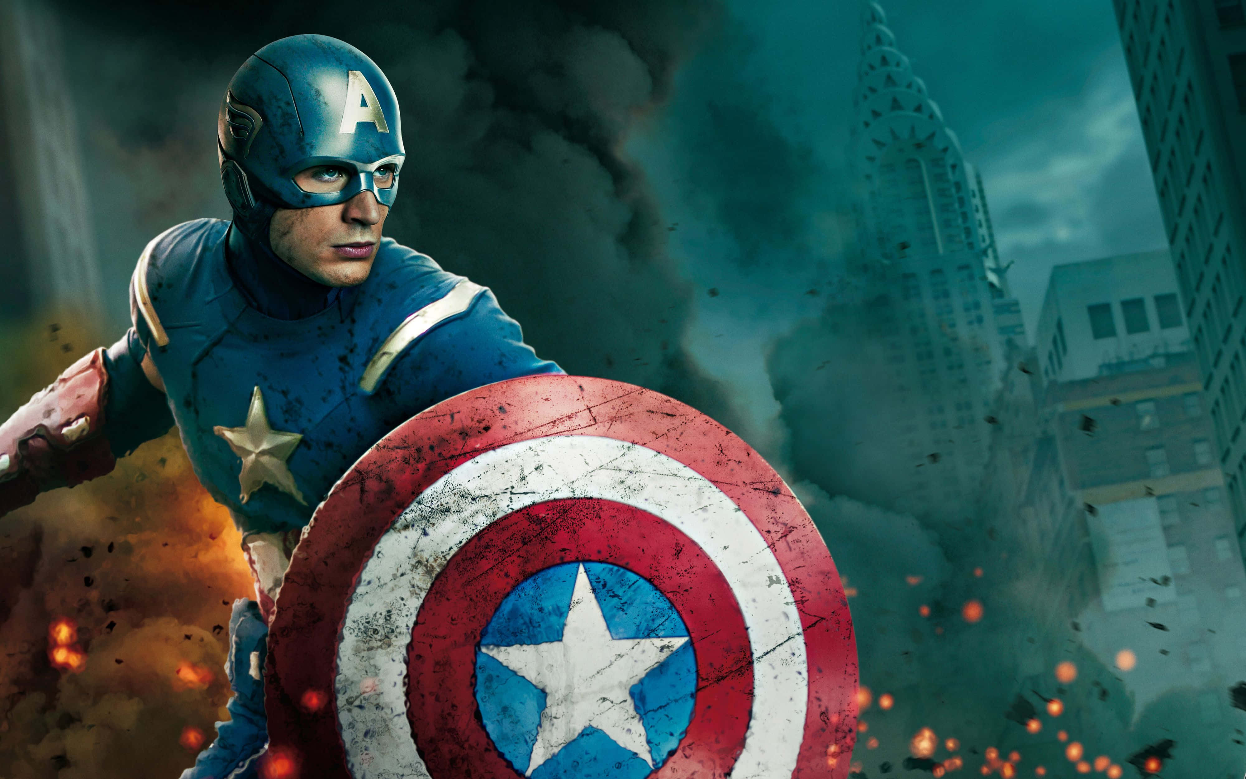 Best Captain America 桌布 壁紙 — 美國隊長在戰火摧殘的城市景觀中堅定站立，手持標誌性盾牌，周圍煙霧和火焰爆發。