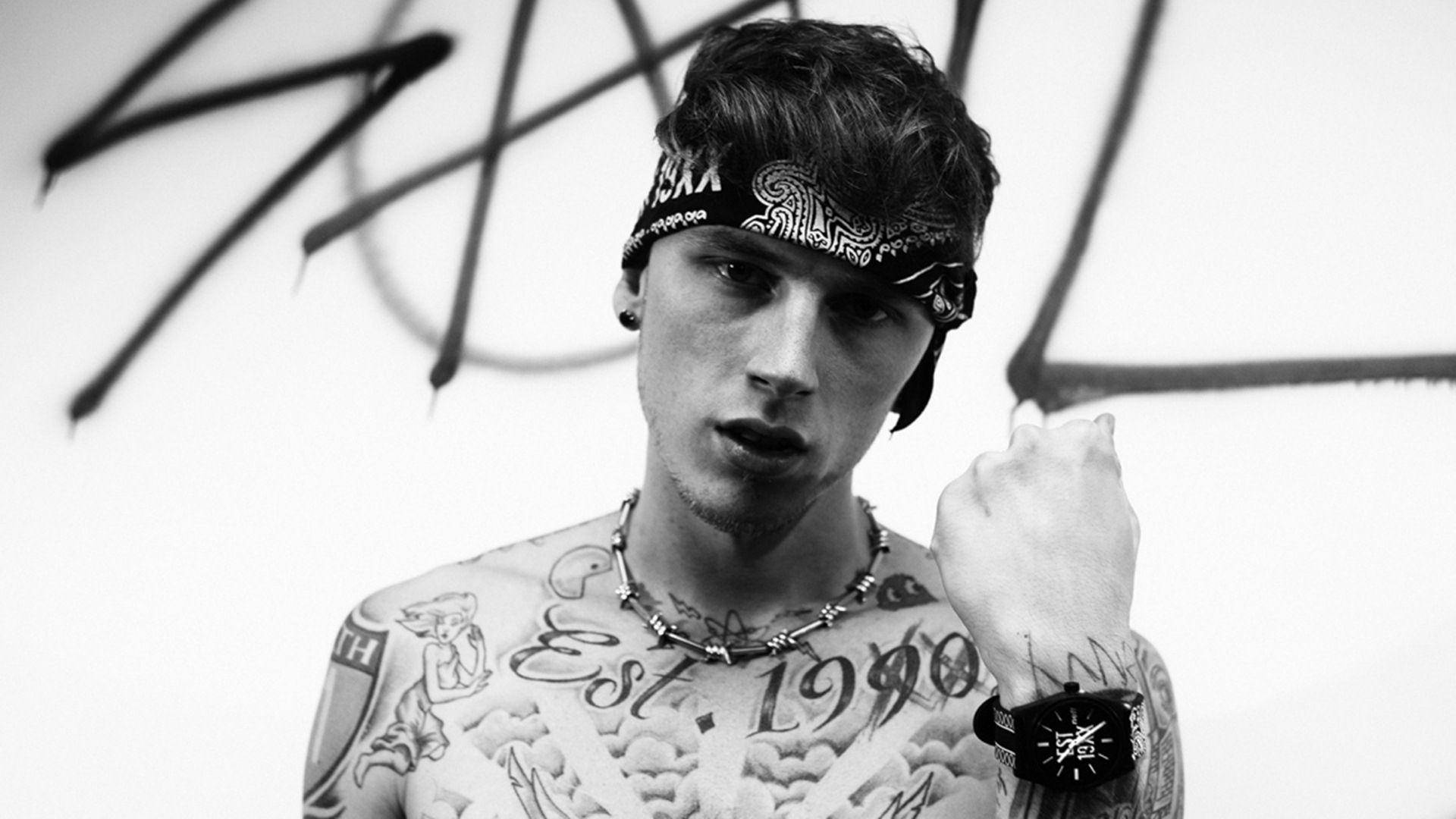 美國饒舌歌手 Machine Gun Kelly 壁紙 — 一位紋身青年戴著頭巾，在黑白塗鴉牆前凝視。