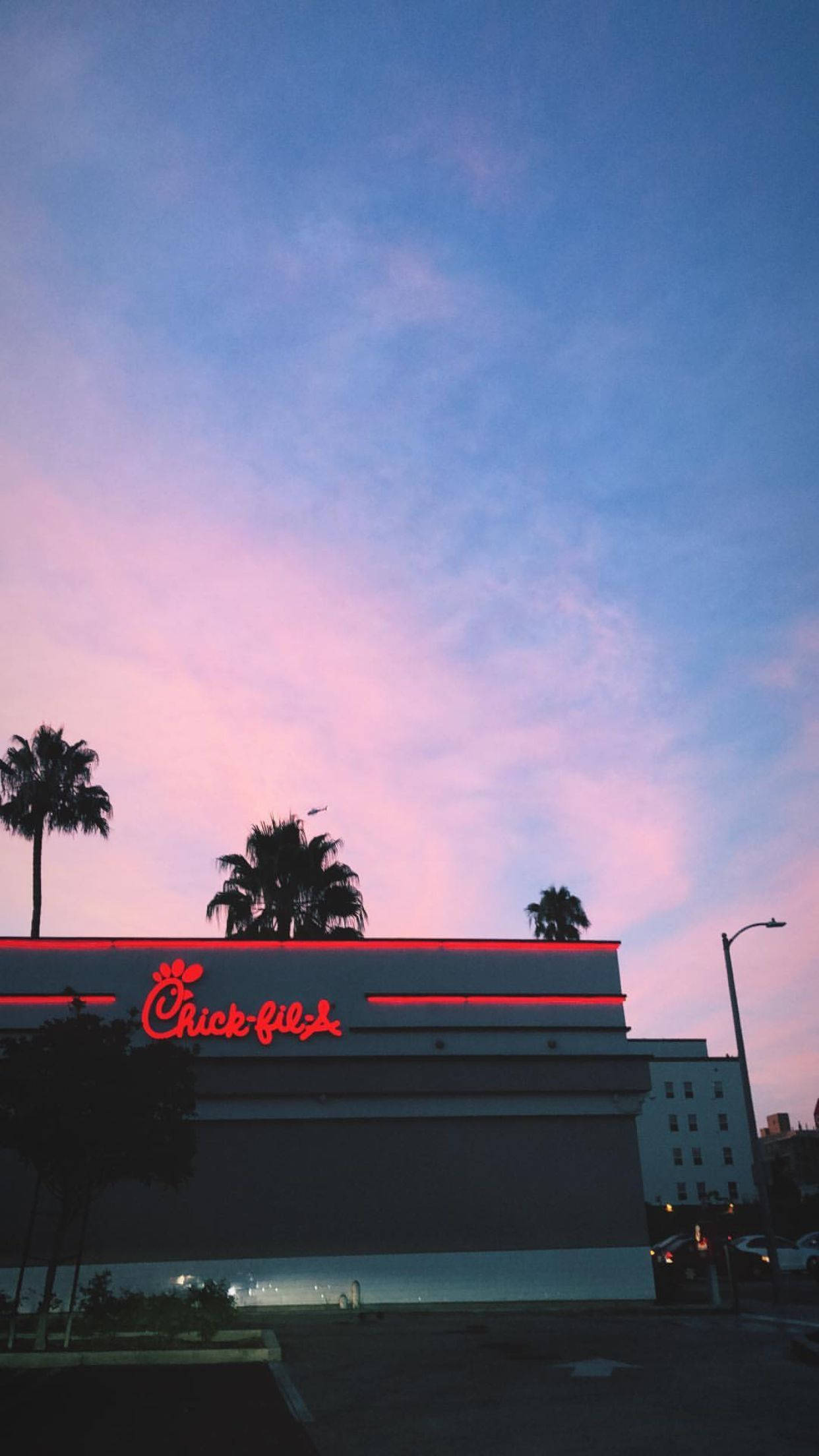 美學 Chick Fil A 廣告牌 壁紙 — 一間Chick-fil-A餐廳在帶有粉紅和藍色雲彩的暮色天空下，散發著紅色霓虹光芒。