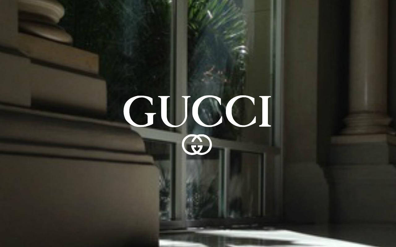 白色Gucci標誌，背景為奢華室內的大理石柱和玻璃門。 — 美學 MacBook 壁紙 壁紙