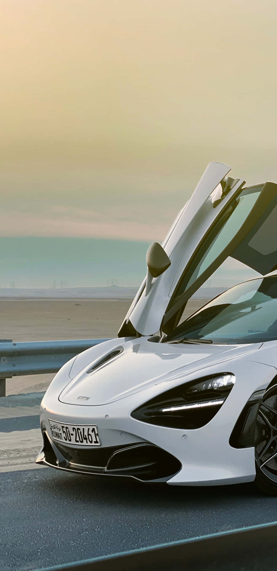 美學像素3XL 麥拉倫720S運動車背景 壁紙 — 一架流線型白色McLaren跑車，在黃金時段的海岸公路上打開鷗翼車門。