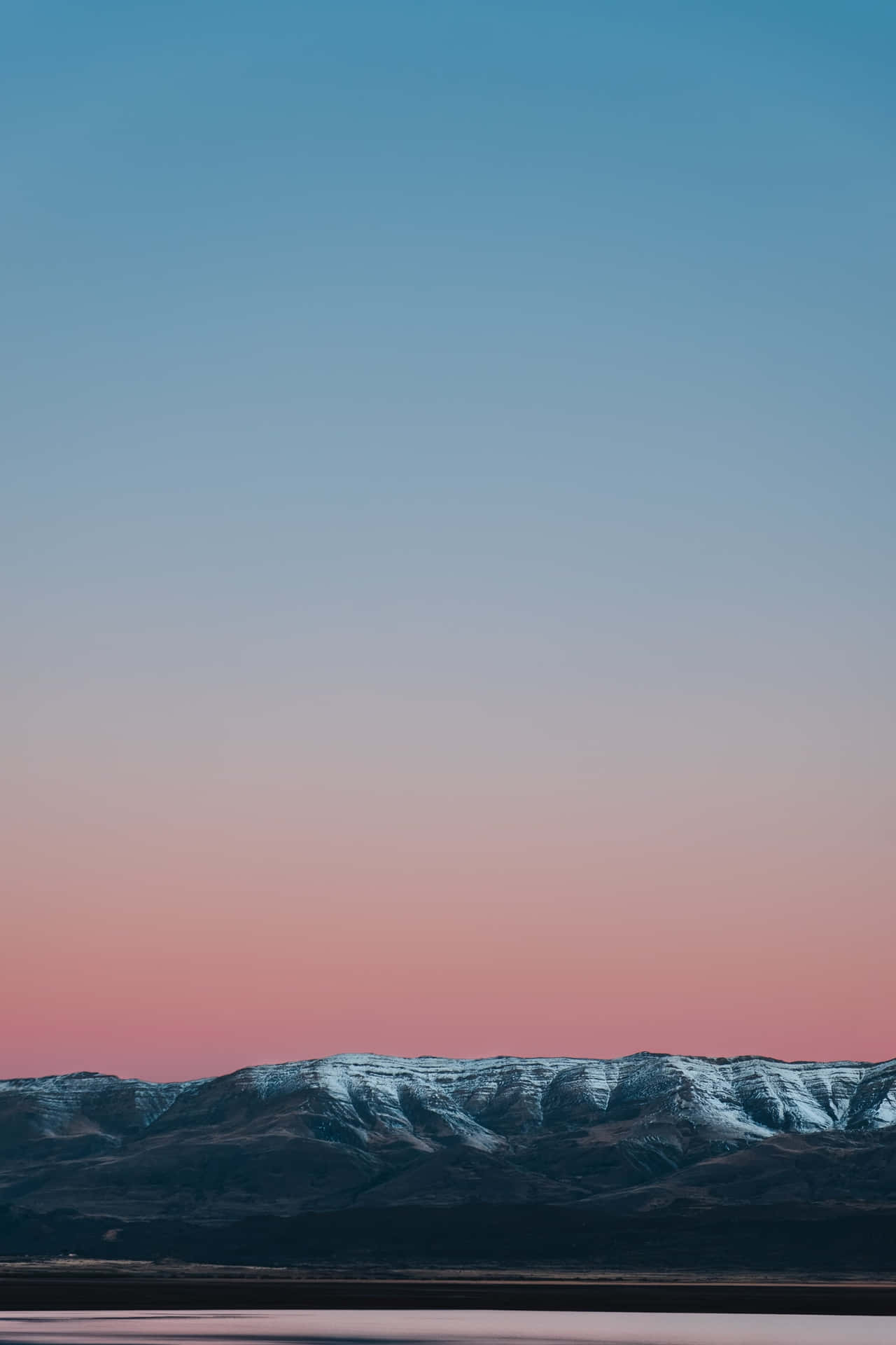 美學手機主畫面藍紅漸變天空 壁紙 — 黃昏時分，白雪覆蓋的山峰在藍粉漸變的天空中形成剪影。