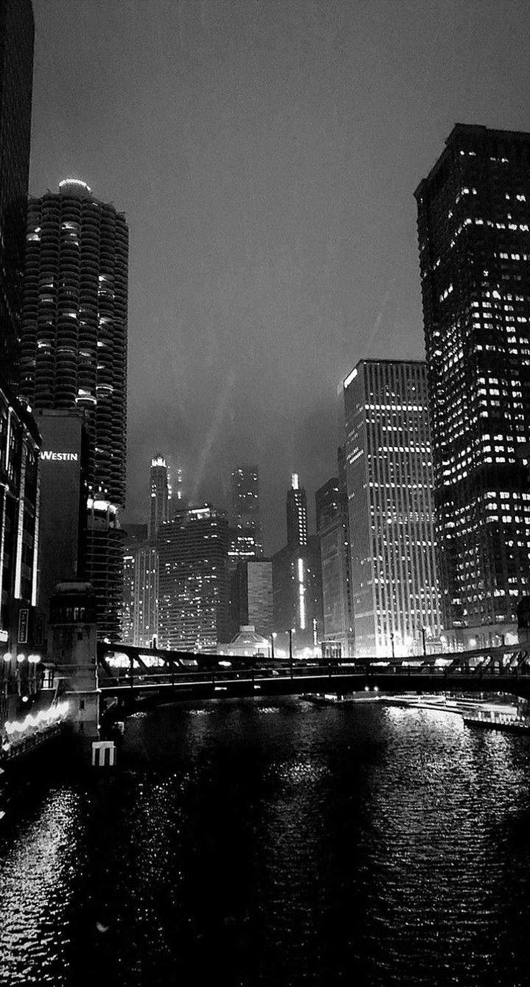 夜間城市天際線，燈火通明的摩天大樓和河流倒影。 — 暗夜城市 壁紙