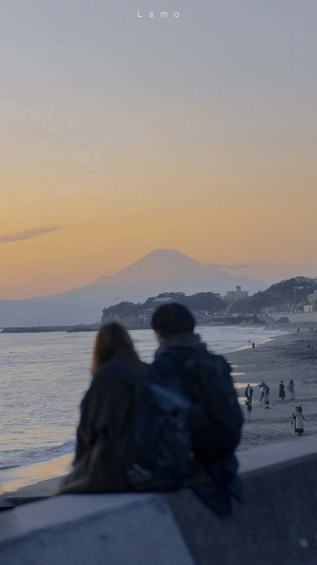 情侶從海邊堤岸觀賞富士山上空的日落