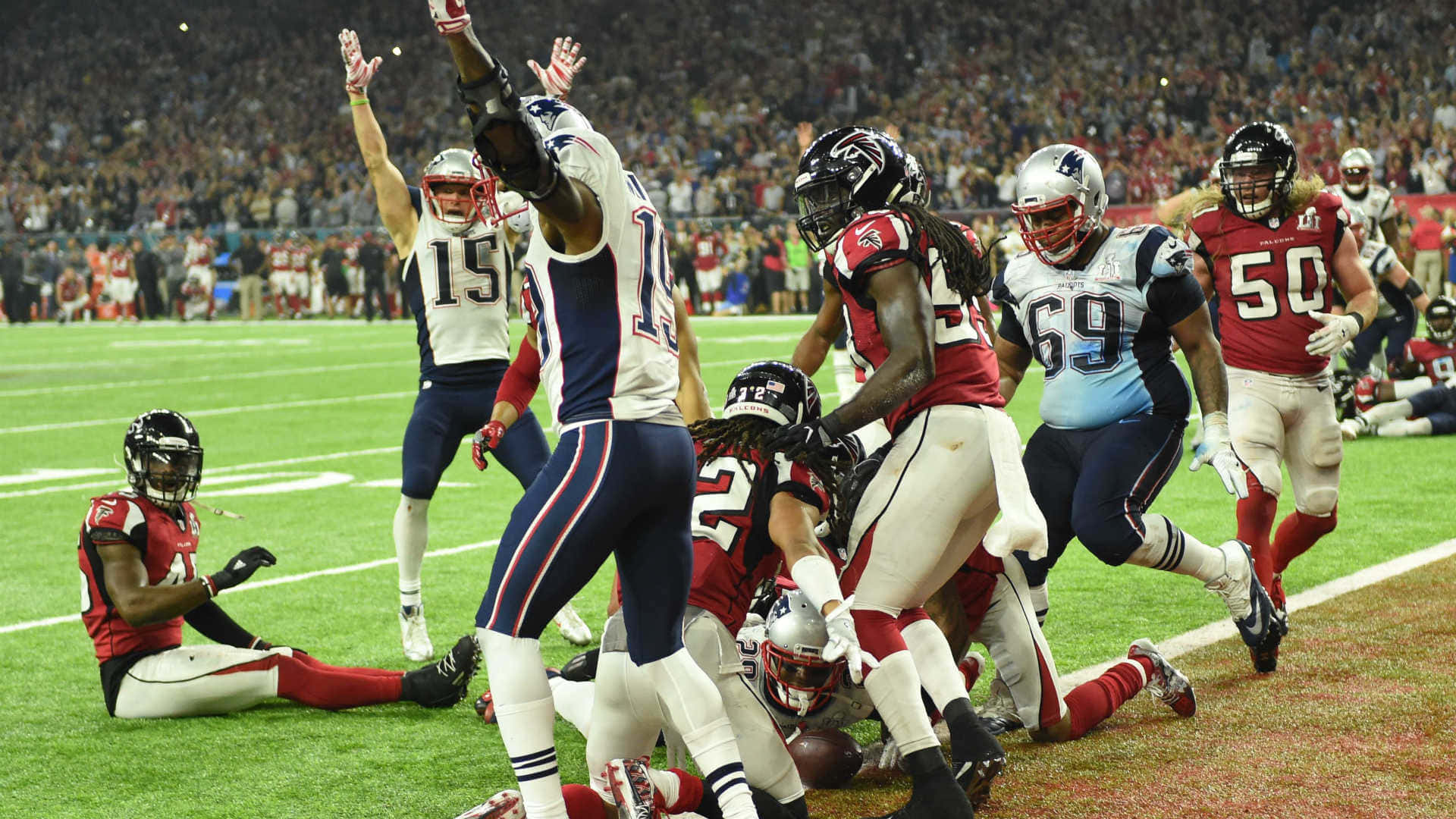 Super Bowl 桌布 壁紙 — 美式足球運動員在燈光球場上比賽，背景有觀眾。