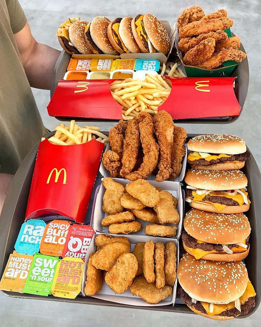 一個托盤堆滿了麥當勞的漢堡、麥樂雞、薯條和醬料包。