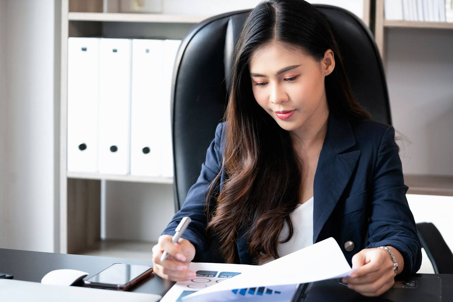 女商人在現代辦公桌上簽署文件。