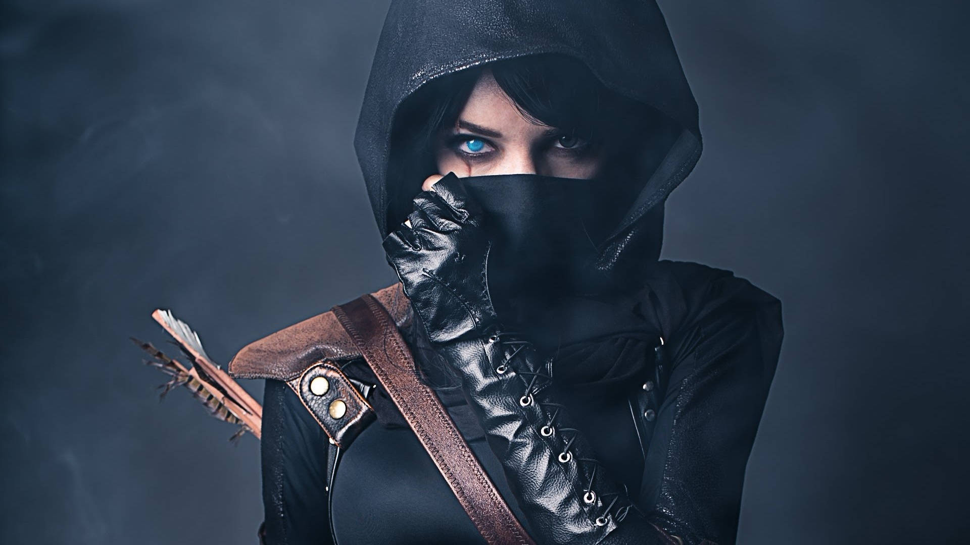 美麗女刺客Cosplay 壁紙 — 一位戴著兜帽的弓箭手，擁有發光的藍色眼睛和皮手套，在煙霧瀰漫的黑暗背景下持弓。