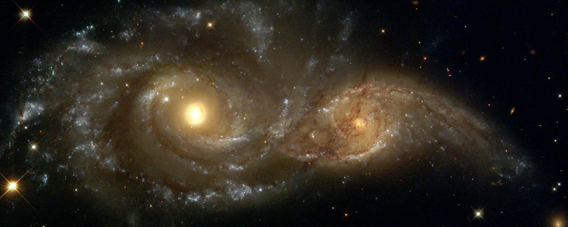 兩個螺旋星系在深空中相撞，有明亮的恆星和發光的塵埃雲。