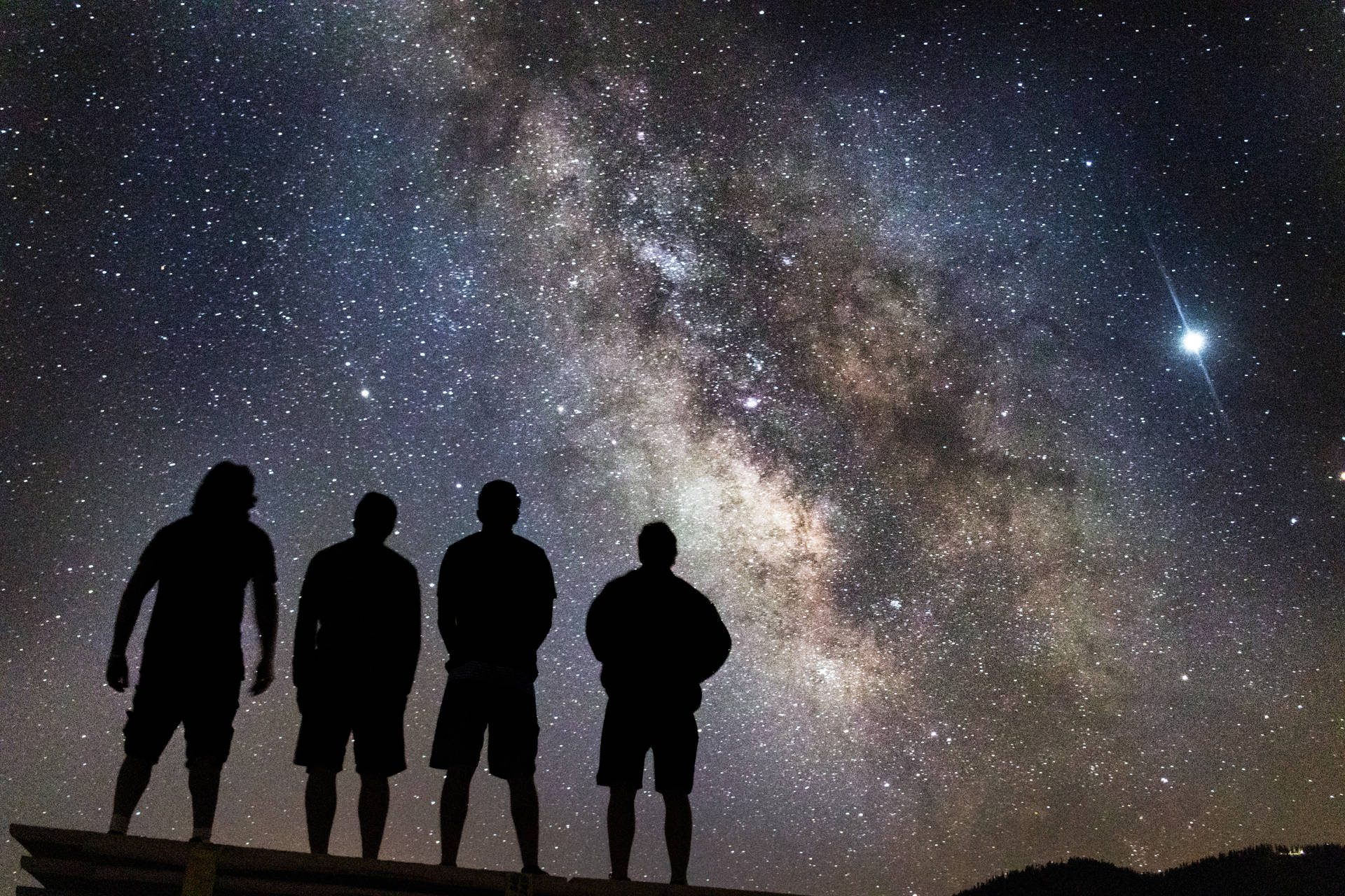 四個人剪影在星空夜空下，銀河系清晰可見。