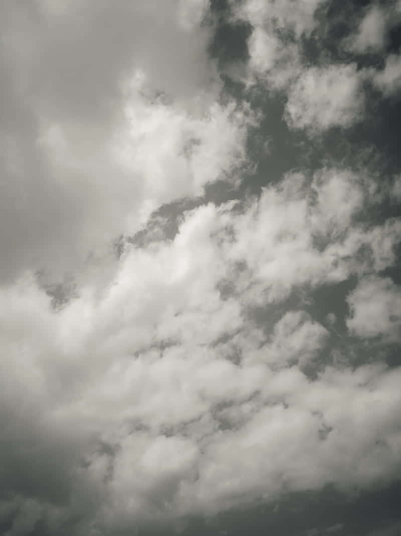 戲劇性的天空，充滿蓬鬆的白雲，背景為灰色。