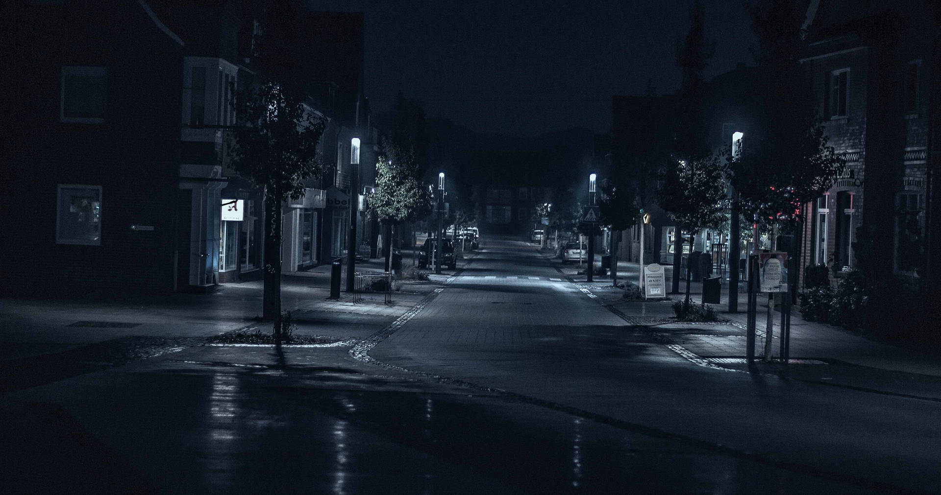 夜晚空無一人的城市街道，濕漉漉的路面反射著路燈。