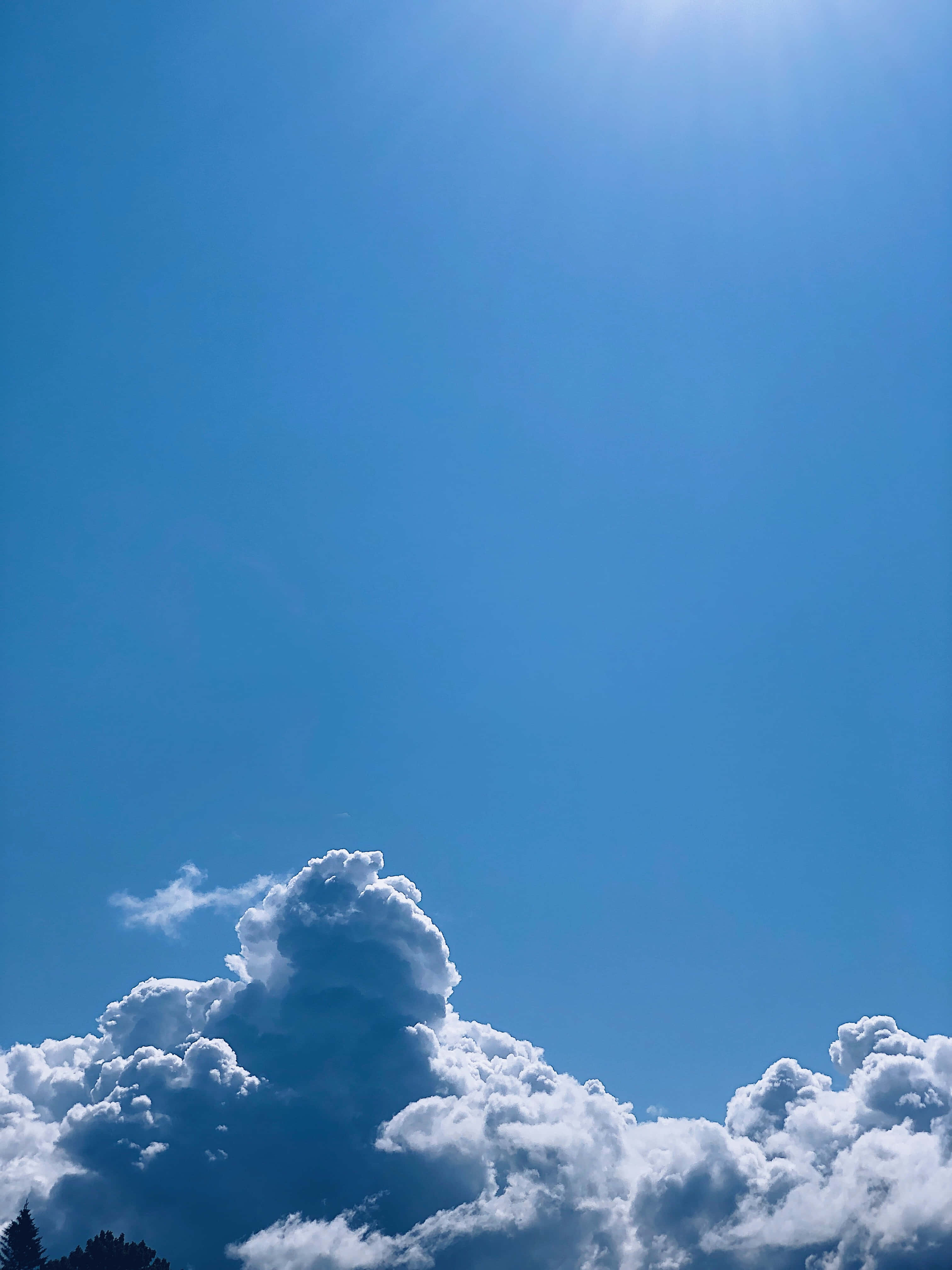 美麗照亮的天空 壁紙 — 廣闊蔚藍天空，蓬鬆白雲和明亮的太陽在頭頂。