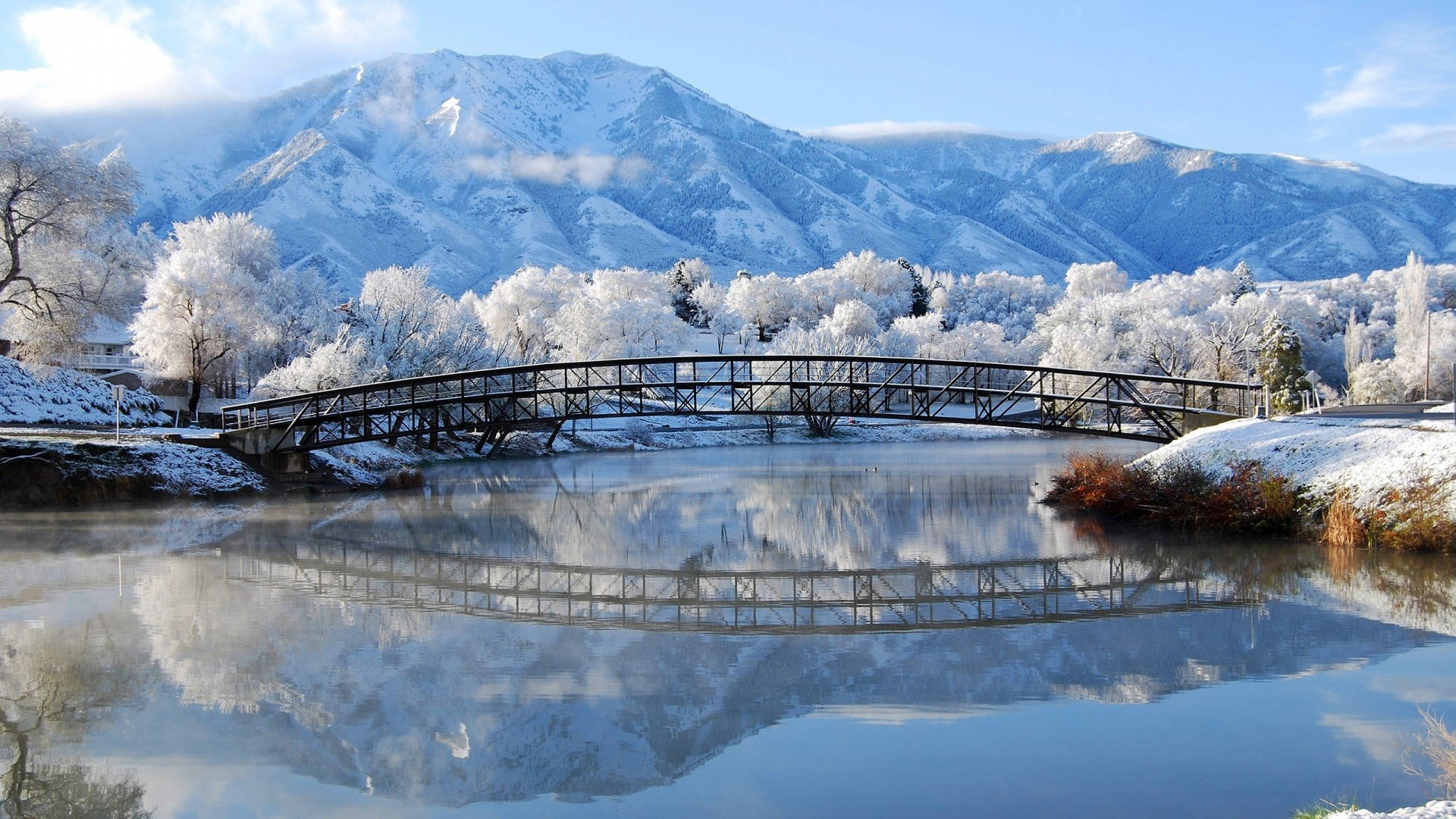 冬季河上雪橋與山巒倒影