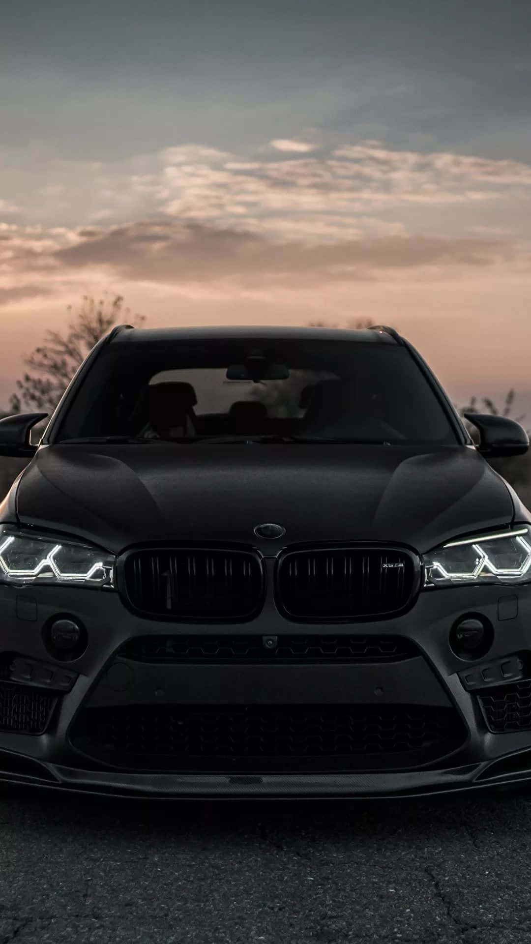 日落中發光的啞光黑色BMW SUV車頭燈。