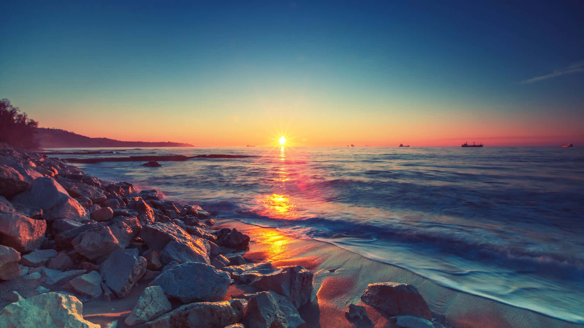 海洋上的夕陽，有岩石和遠處的船隻